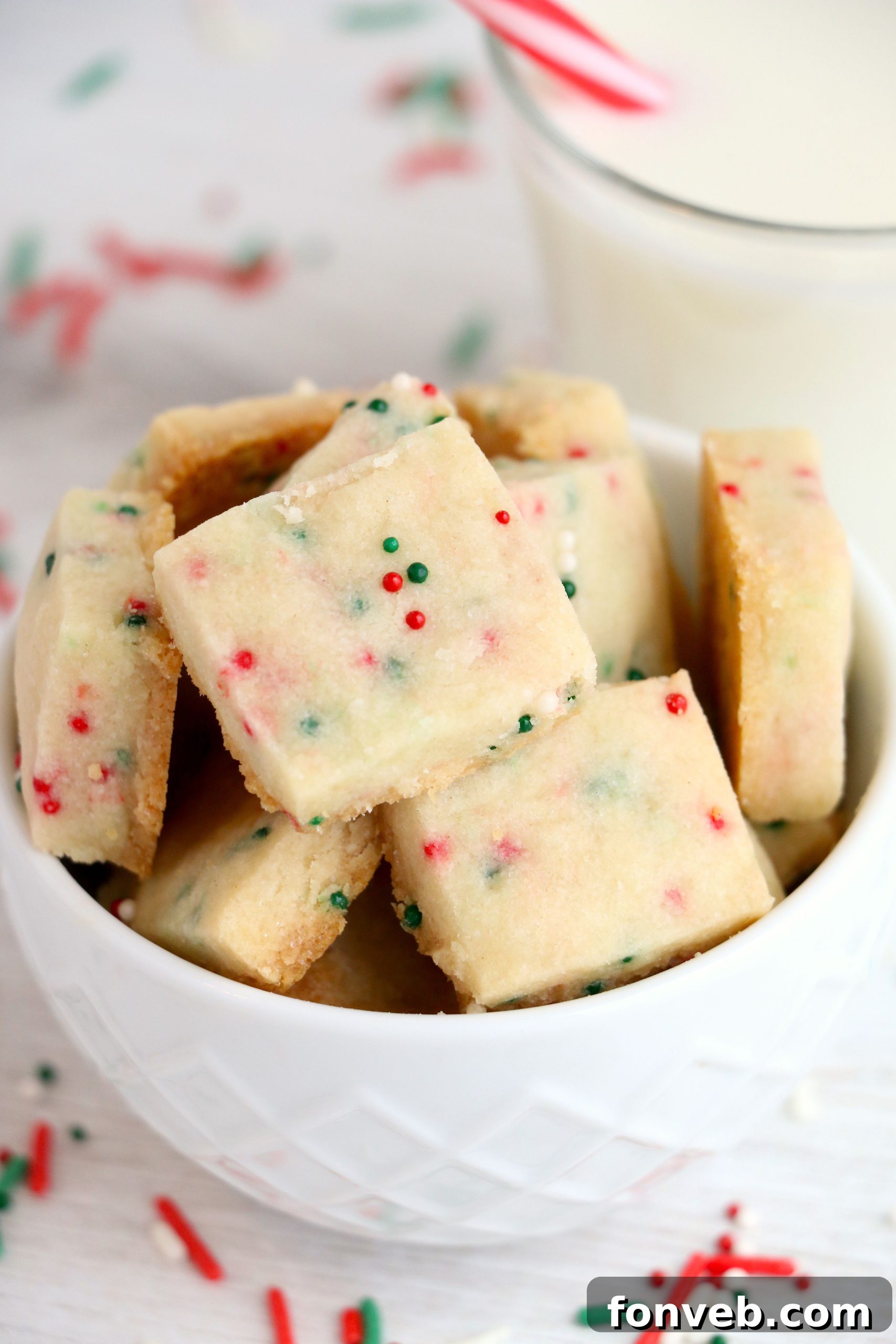 Four Ingredient Festive Shortbread Bites 4 A hand gently holding a perfectly baked Christmas Shortbread Cookie Bite, showcasing its golden edge and vibrant sprinkles.