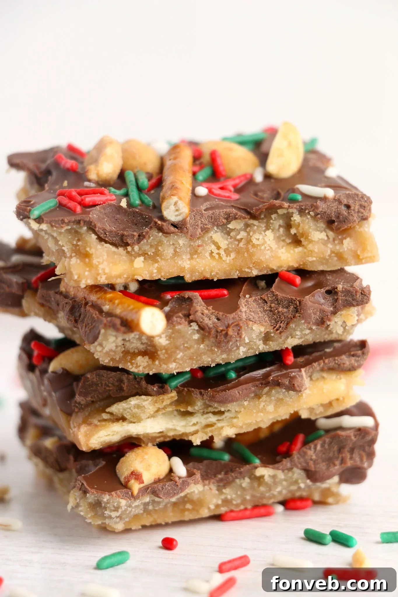 Toffee Pretzel Peanut Bark 2 Delicious Pretzel Peanut Cracker Toffee on a white tray, showing its layers of cracker, toffee, chocolate, pretzels, and peanuts.