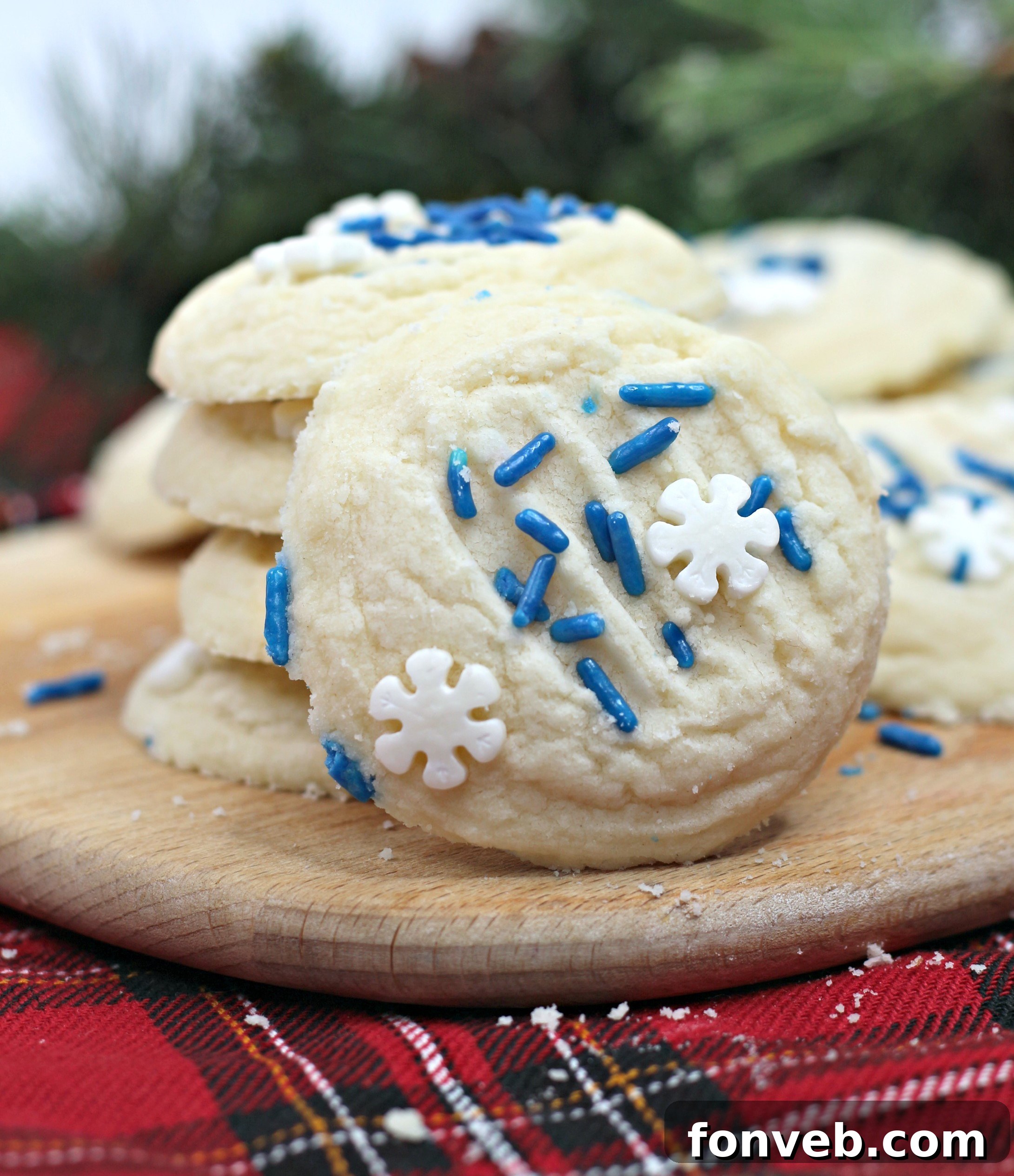 Close-up of freshly baked whipped shortbread cookies with blue and white sprinkles, arranged artfully on a white surface.