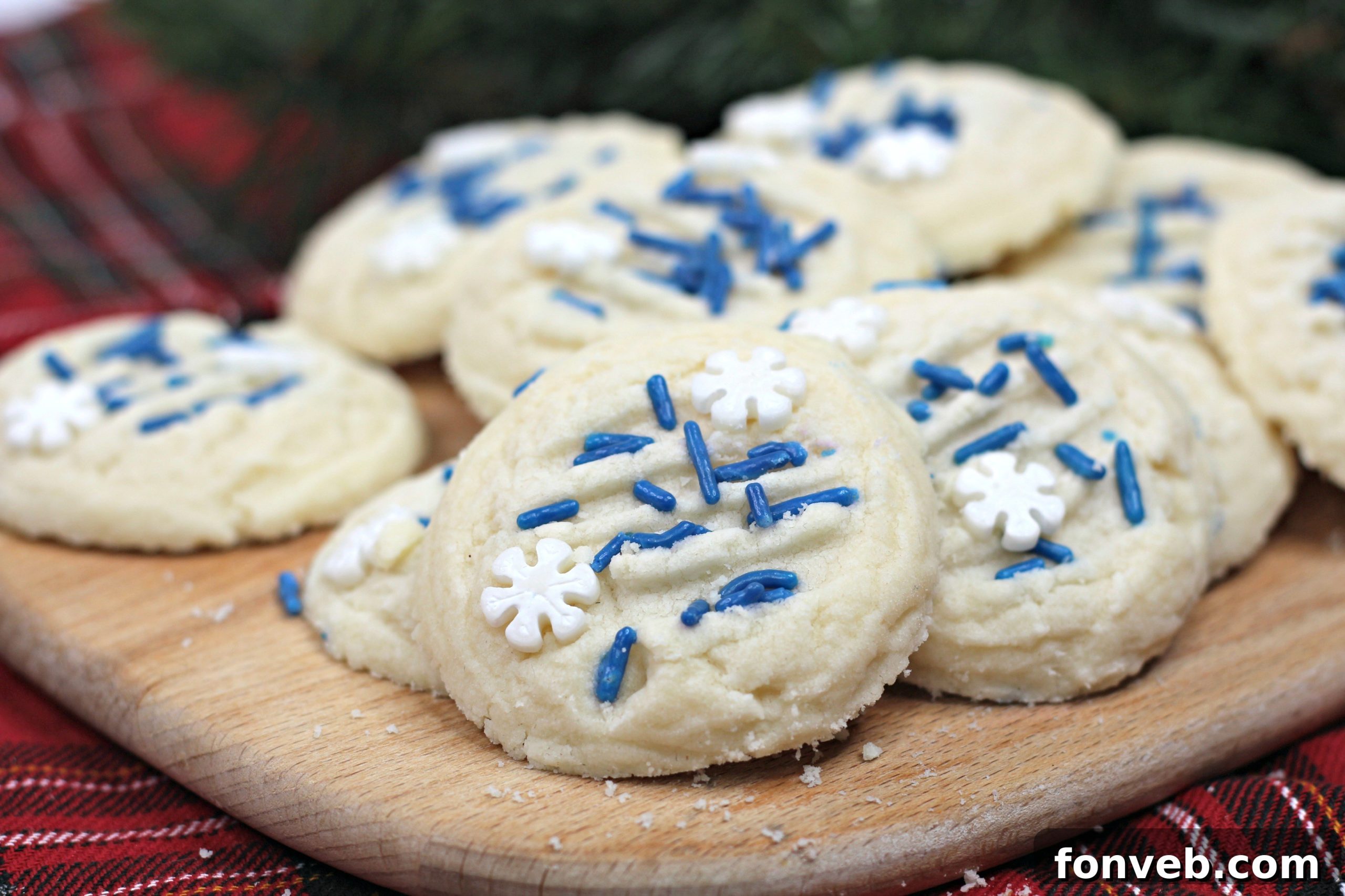 A plate of round whipped shortbread cookies, some with blue and white sprinkles, against a light background.