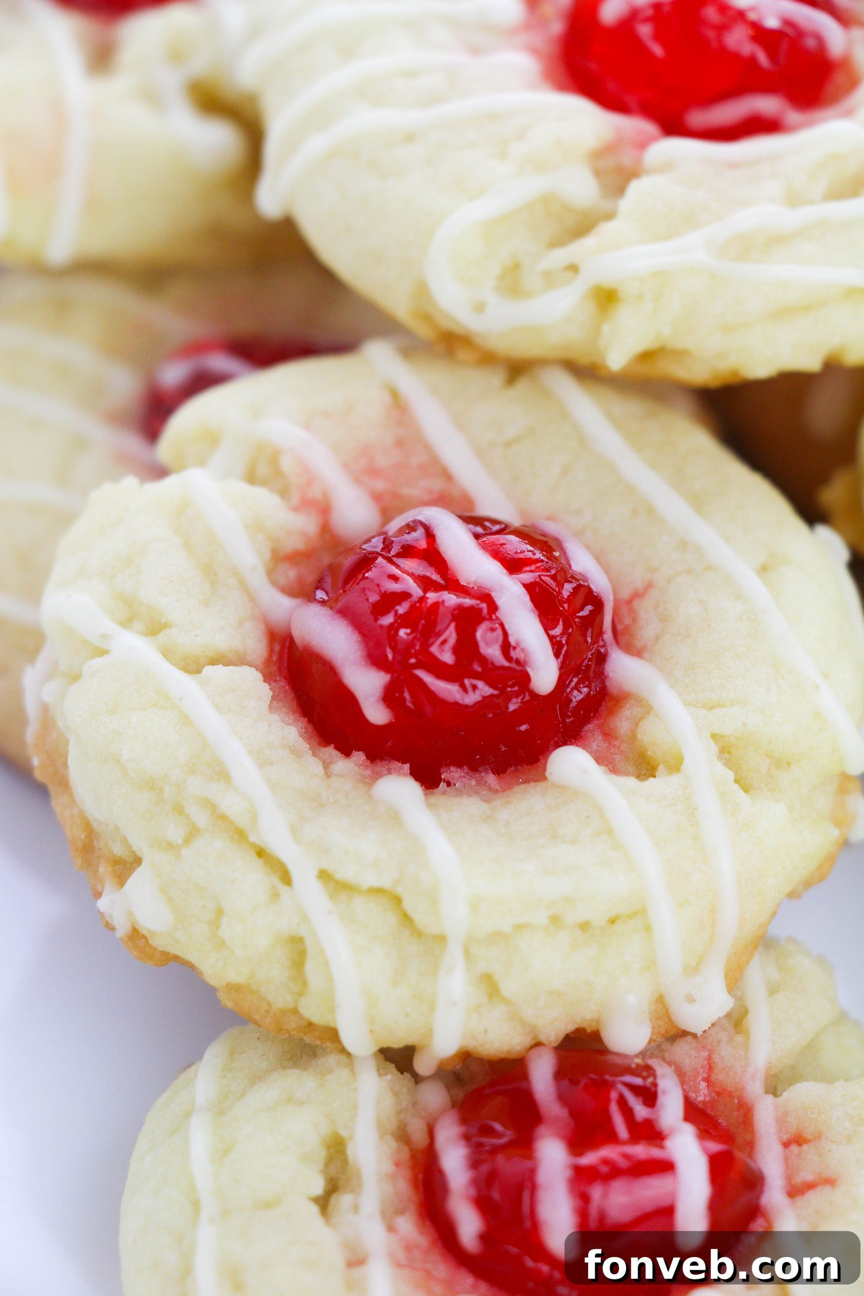 A stack of Eggnog Thumbprint Cookies showing their soft interior and cherry filling