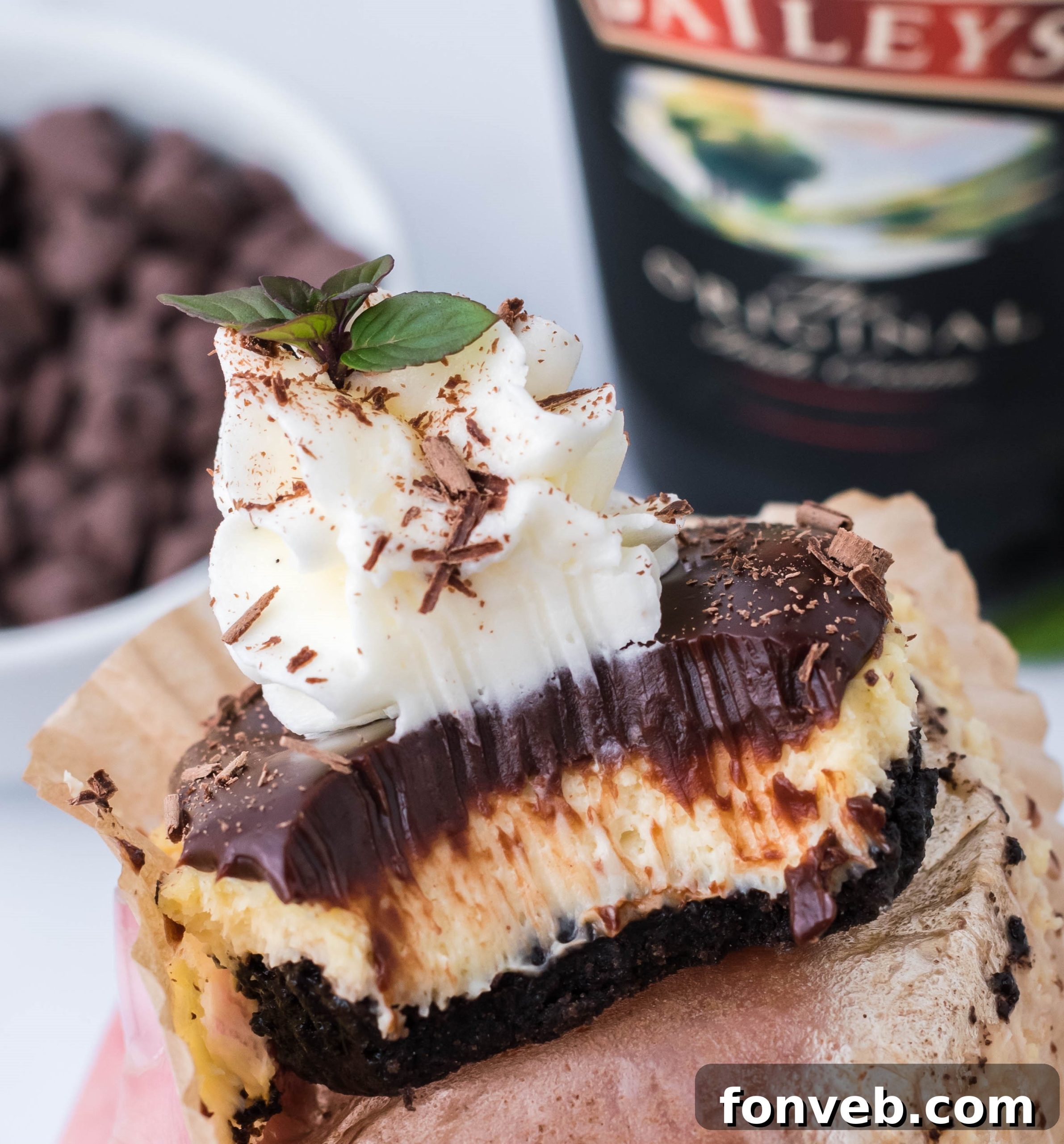 Close-up of a mini Baileys cheesecake topped with chocolate ganache and chocolate shavings