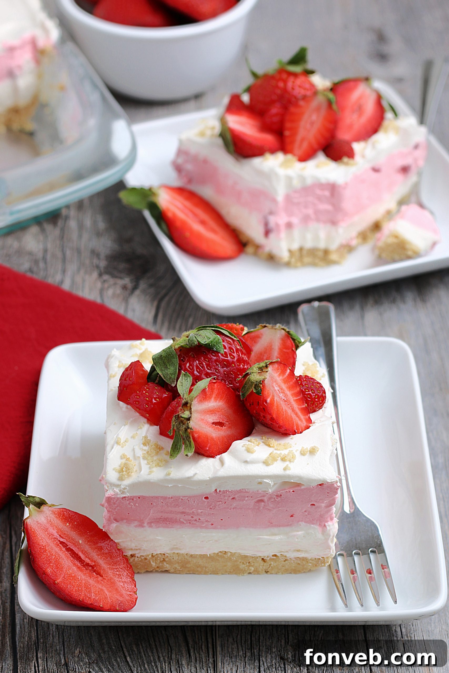 Close-up of a single slice of strawberry cheesecake lasagna on a white plate, showcasing all four delicious layers