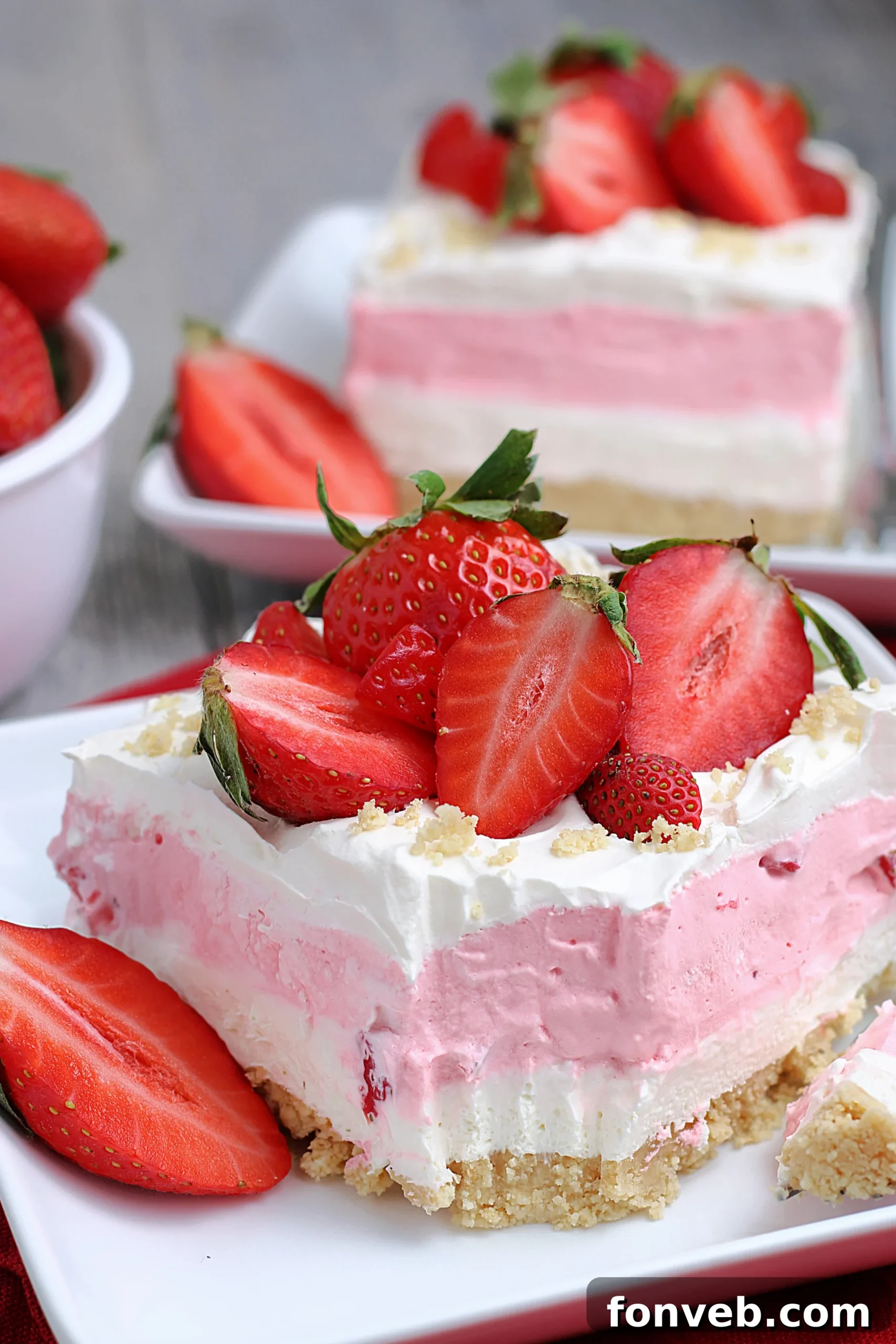 Overhead shot of No-Bake Strawberry Cheesecake Lasagna garnished with fresh strawberries and cookie crumbs