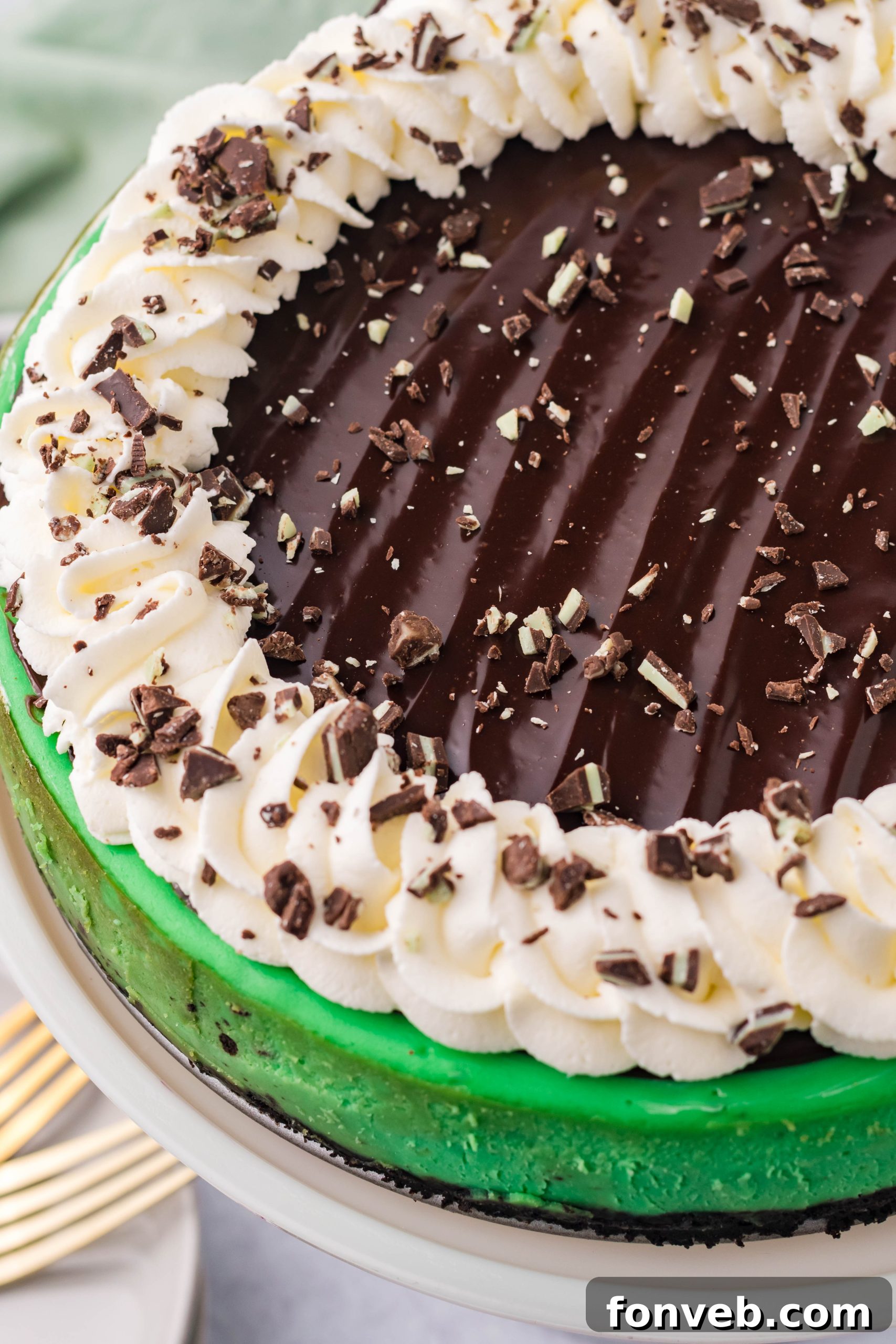 A close-up shot of the vibrant green Grasshopper Cheesecake with its chocolate crust