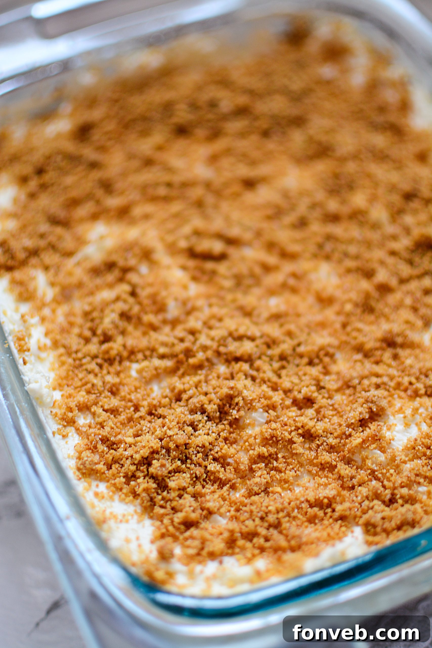 Another enticing view of the pineapple cream dessert in a pan, highlighting its inviting golden crust and the smooth, pale yellow top layer, garnished with fresh pineapple slices.