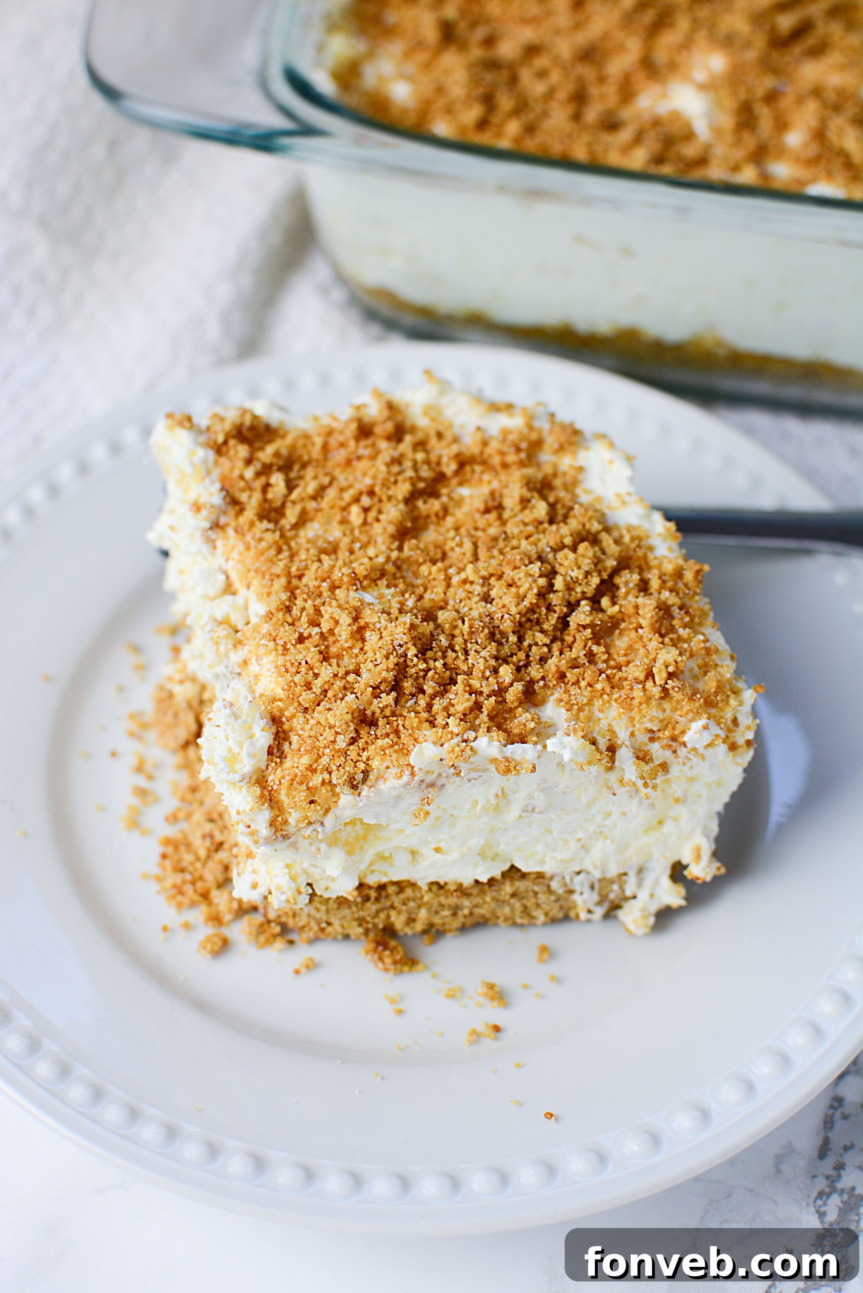 A close-up of a serving spoon scooping into the fluffy, creamy pineapple dessert, showing the rich texture and tempting layers.