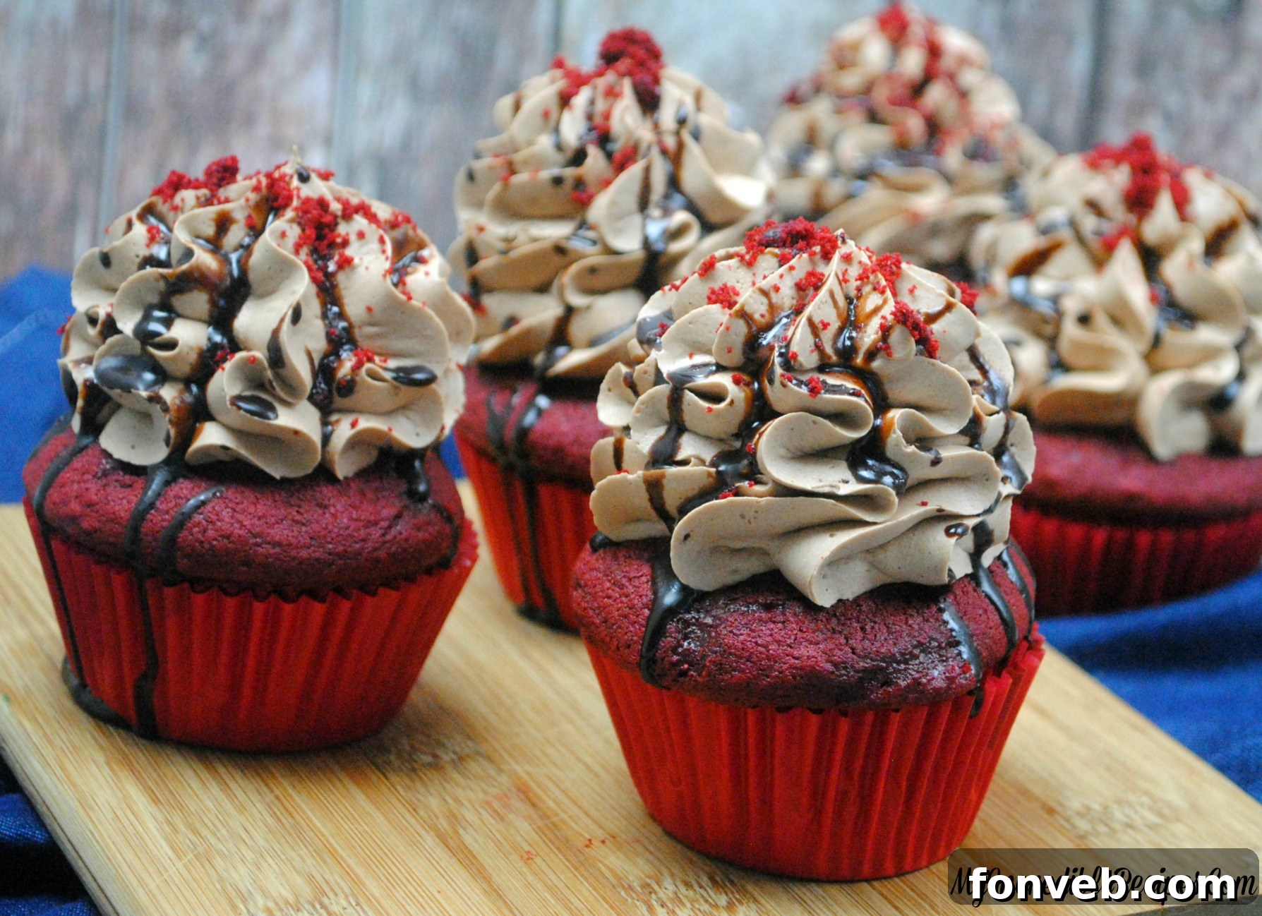 Garnished red velvet cupcakes with chocolate cream cheese frosting, fudge, and caramel