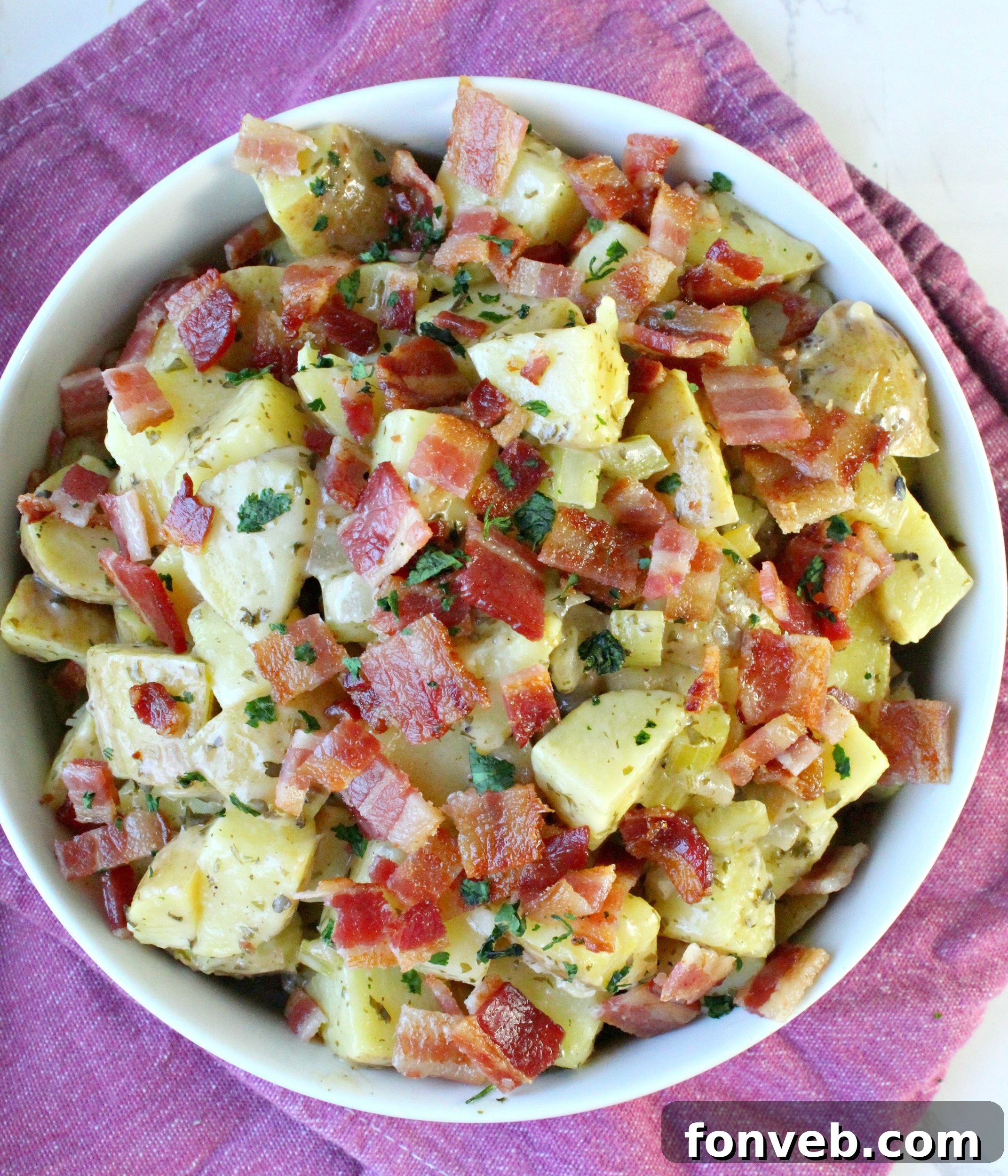 Tangy German Potato Salad 3 Close-up of German Potato Salad with visible bacon pieces and parsley.