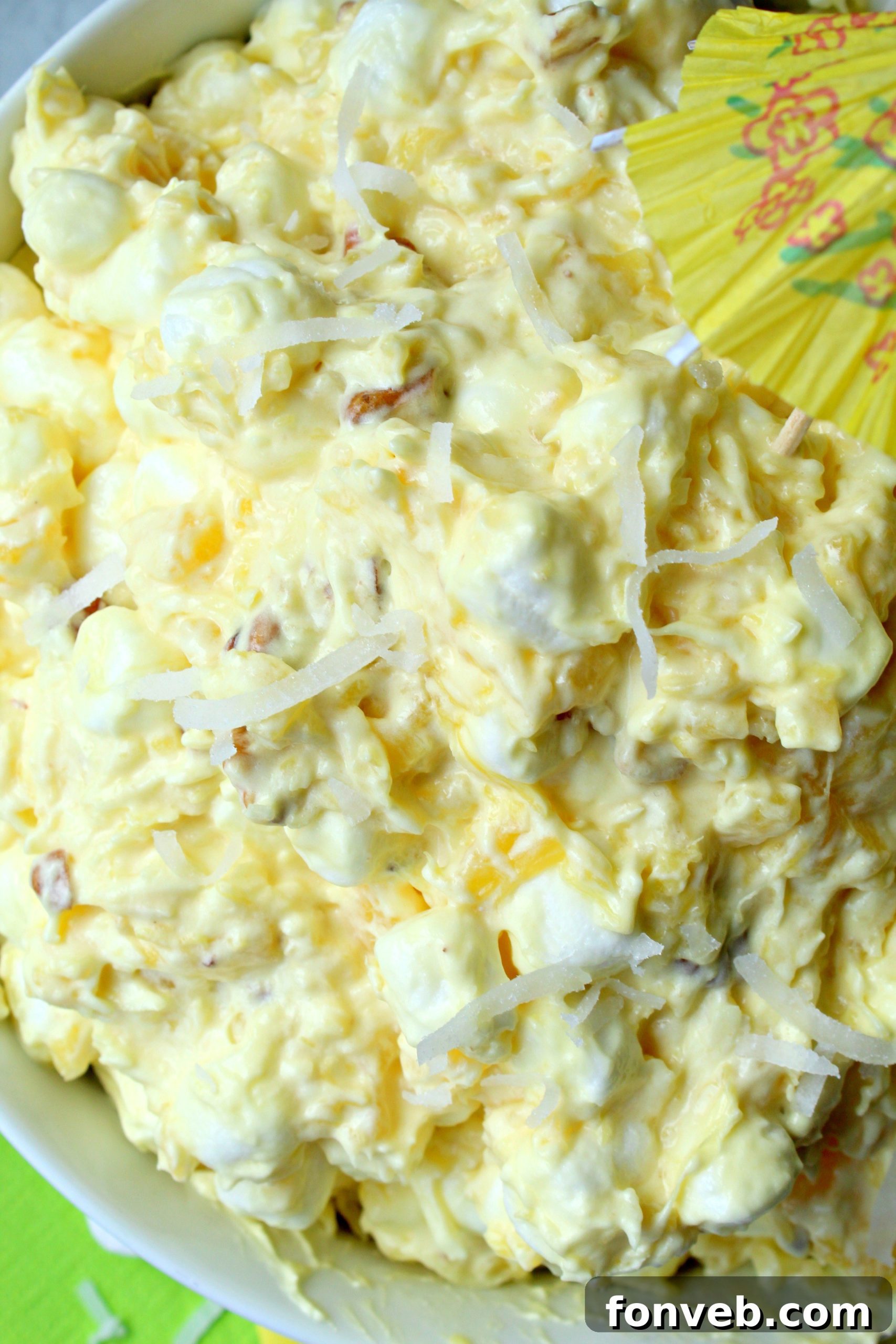 Up close shot of Piña Colada Fluff in a white bowl, showing the creamy texture and small pineapple pieces.