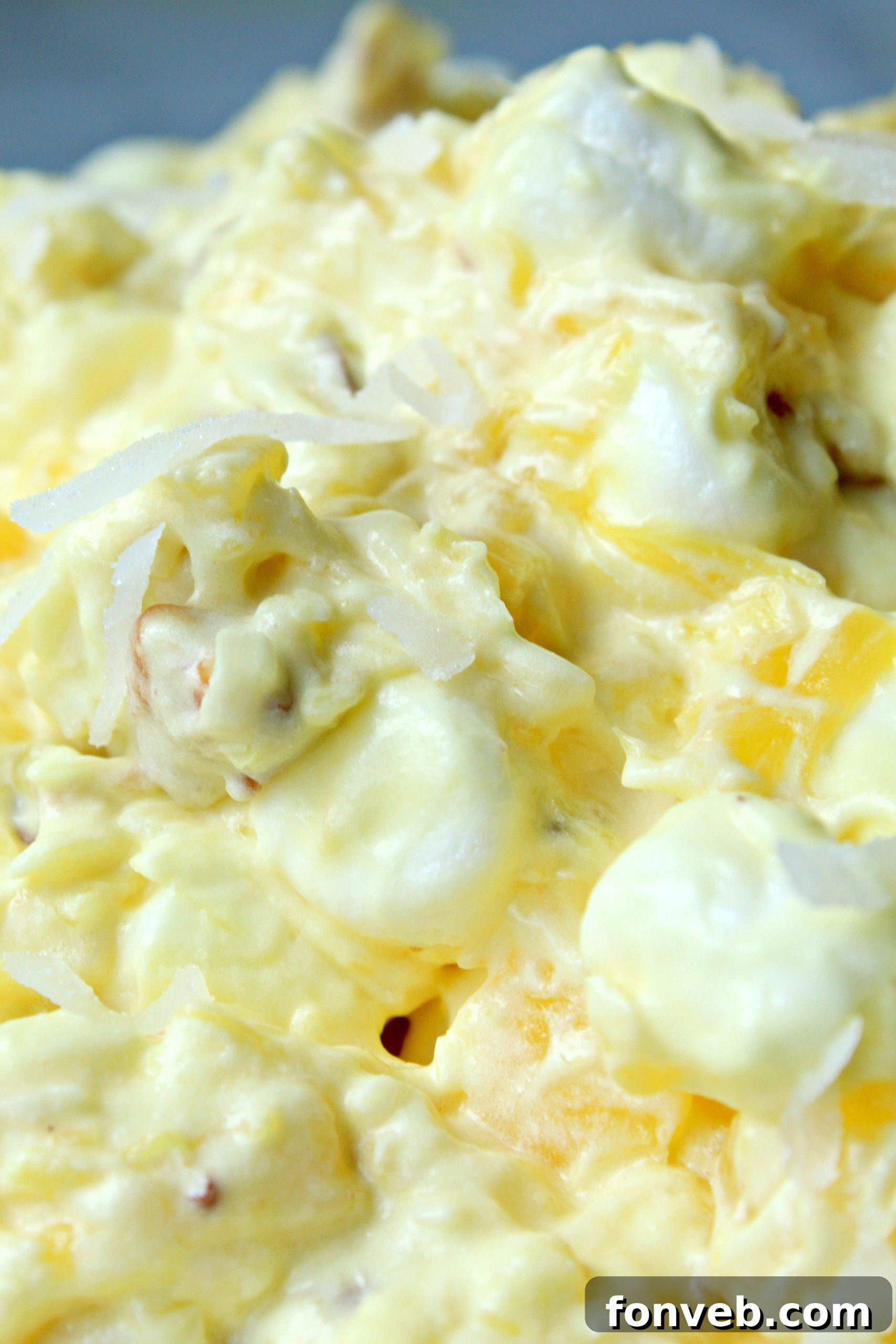 A bowl of Piña Colada Fluff with a serving spoon.