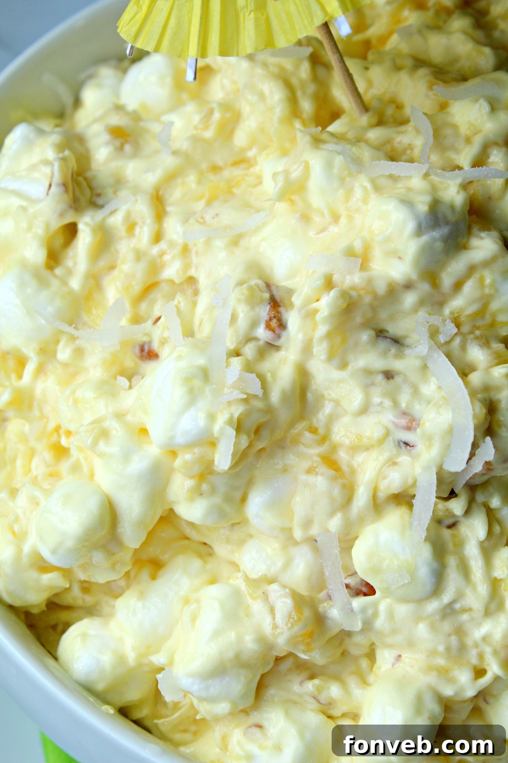 A bowl of Piña Colada Fluff with a spoon, showing its creamy and chunky texture.
