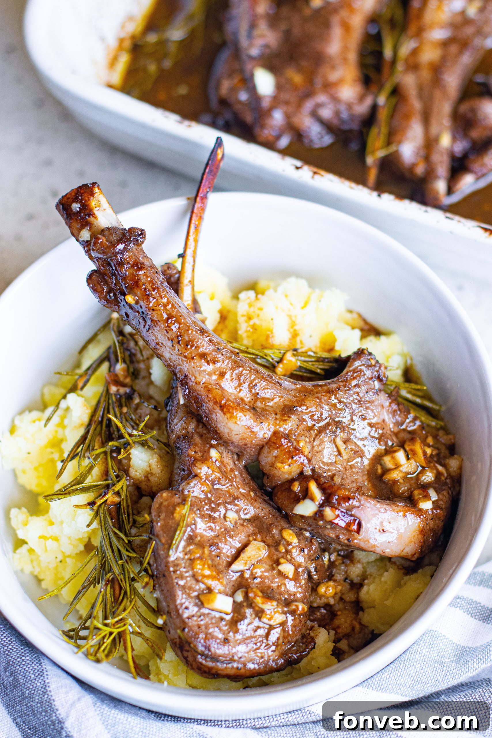 Hands pouring the balsamic garlic marinade over seasoned lamb chops in a baking dish