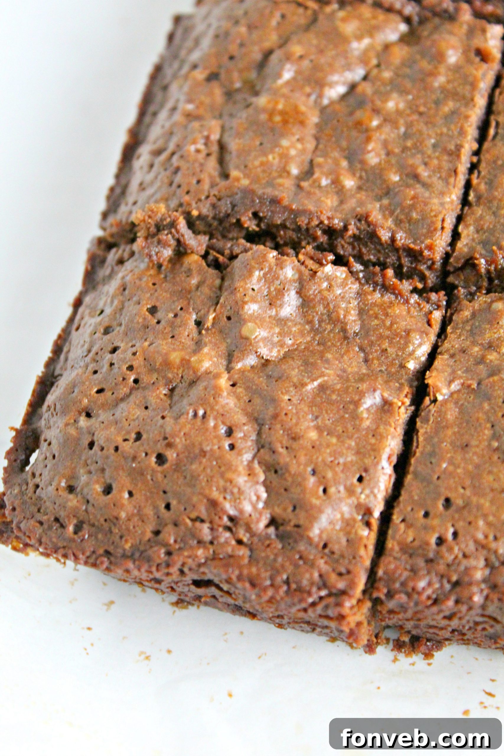 A close-up shot of a single Dr. Pepper brownie square, revealing its dense, fudgy interior and slightly crinkled top, with some chocolate chips peeking through.