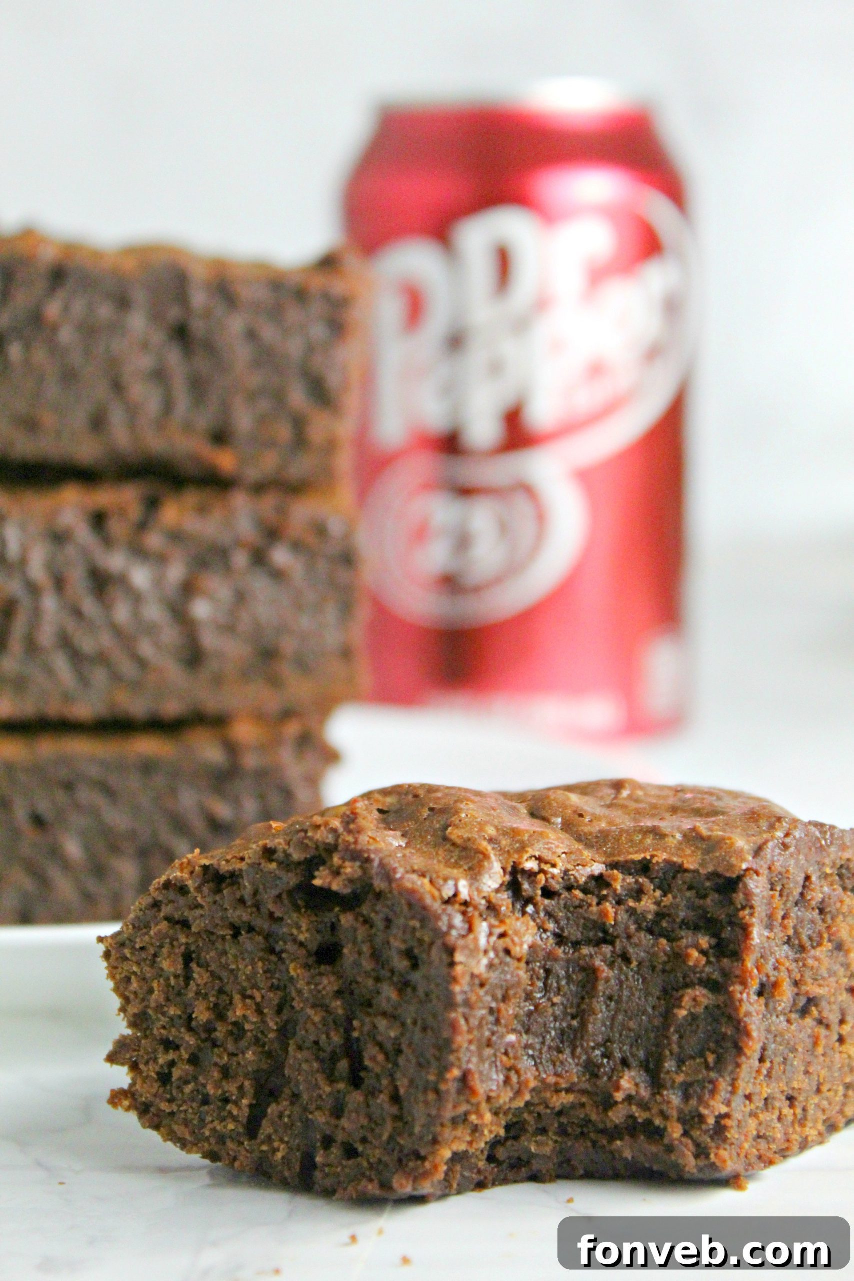 A warm Dr. Pepper brownie being carefully lifted from the baking dish, steam subtly rising, highlighting its fresh-from-the-oven appeal.