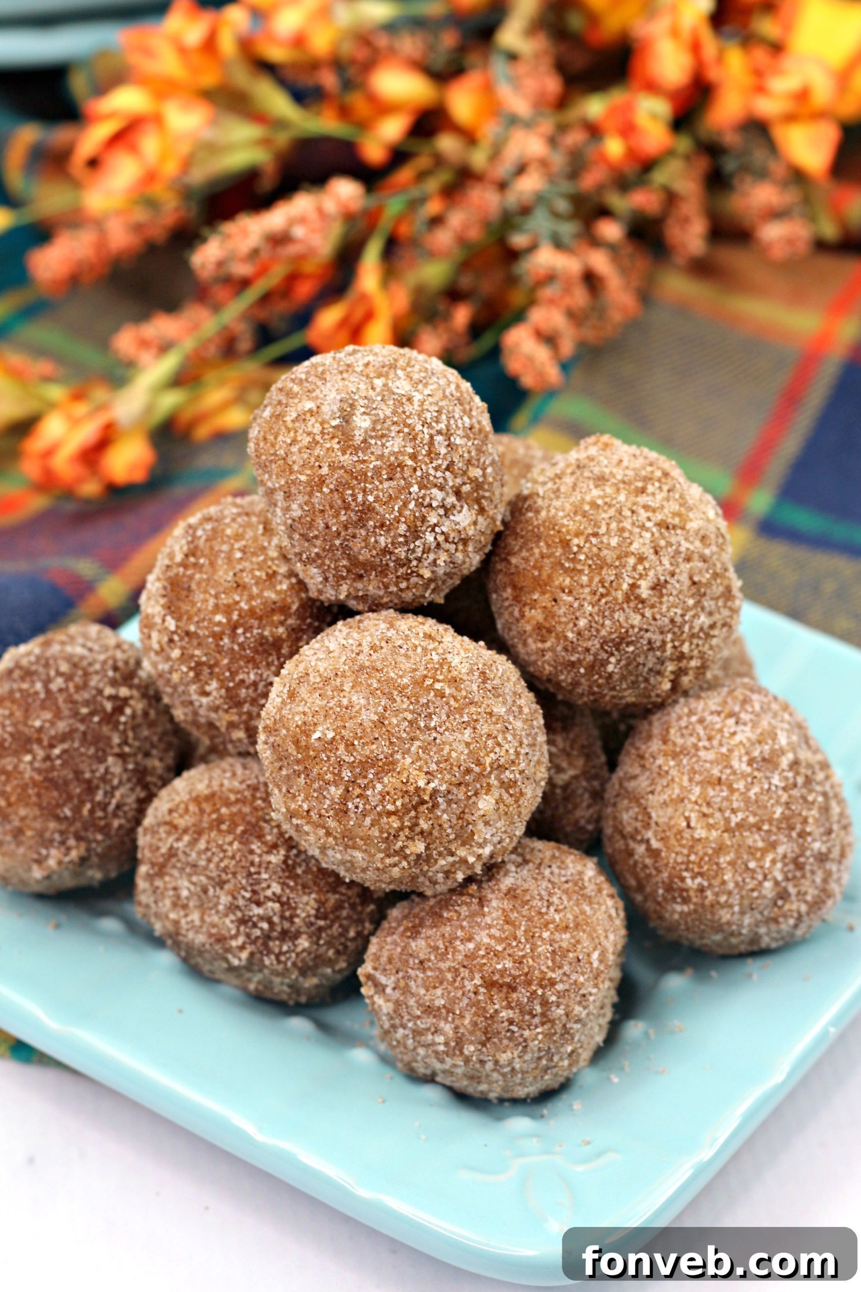 Pumpkin snickerdoodle donut holes, some with a bite taken, showcasing their soft interior
