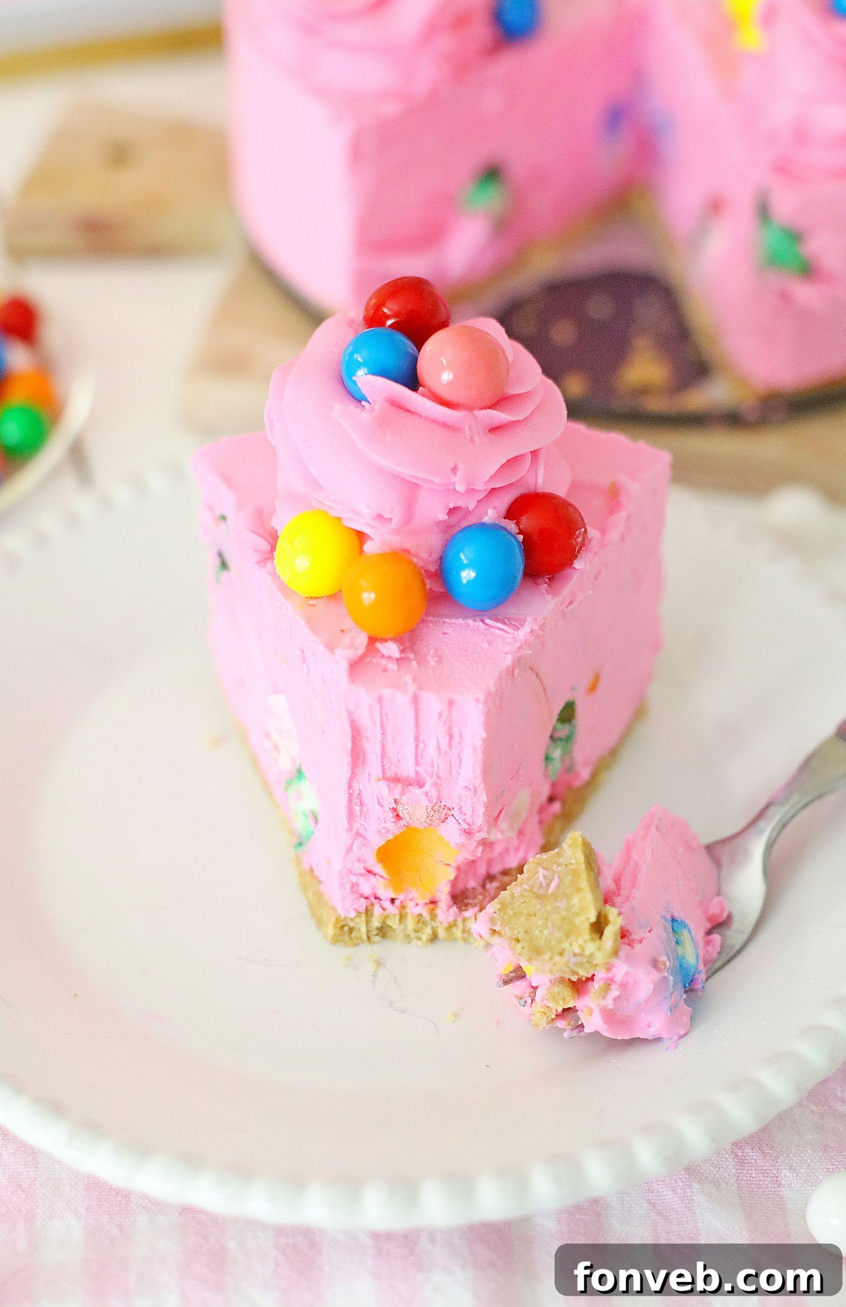 Vibrant pink bubblegum cheesecake with gumballs scattered inside, a slice partially cut, sitting on a colorful plate, ready to be served at a party or celebration.