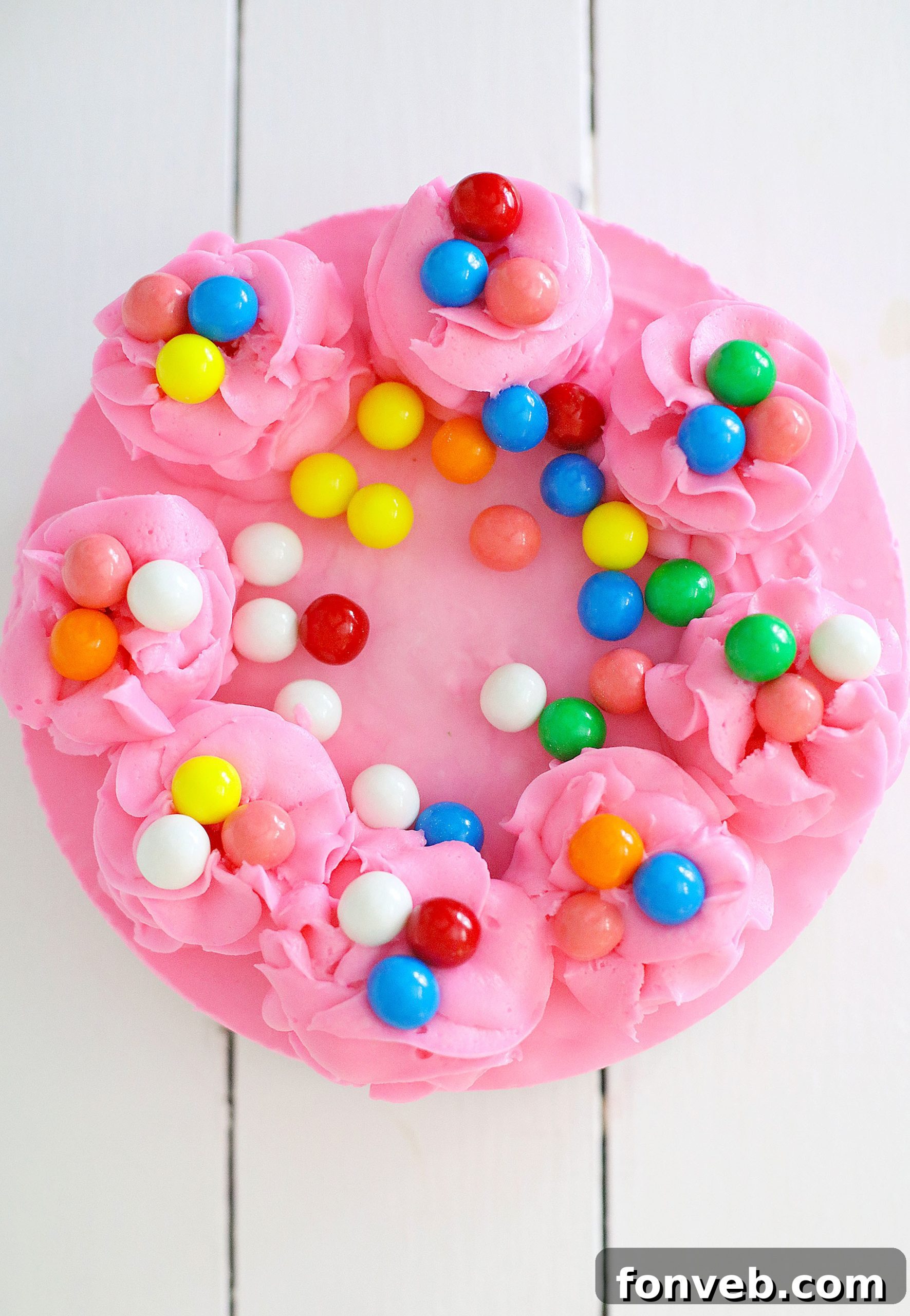 The finished no-bake bubblegum cheesecake, beautifully decorated with piped pink frosting dollops and additional gumballs on top, presented in a springform pan.