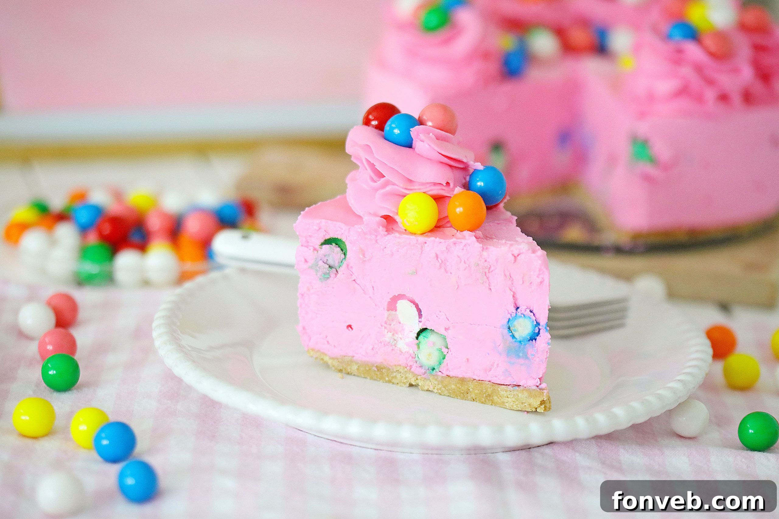 Overhead shot of the entire bubblegum cheesecake, freshly decorated with piped frosting and extra gumballs, ready for cutting and serving.