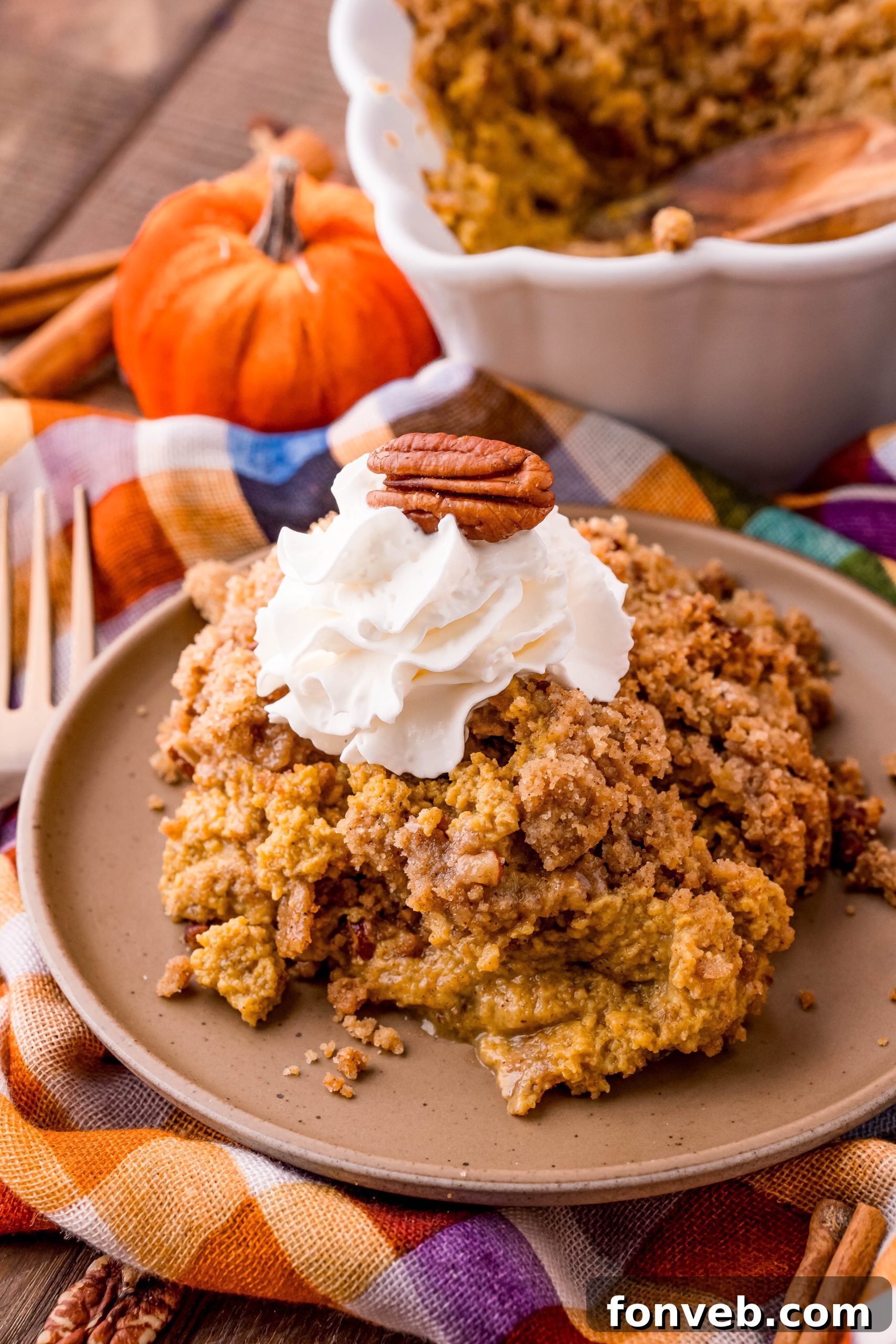 A slice of pumpkin crisp with whipped cream on a plate