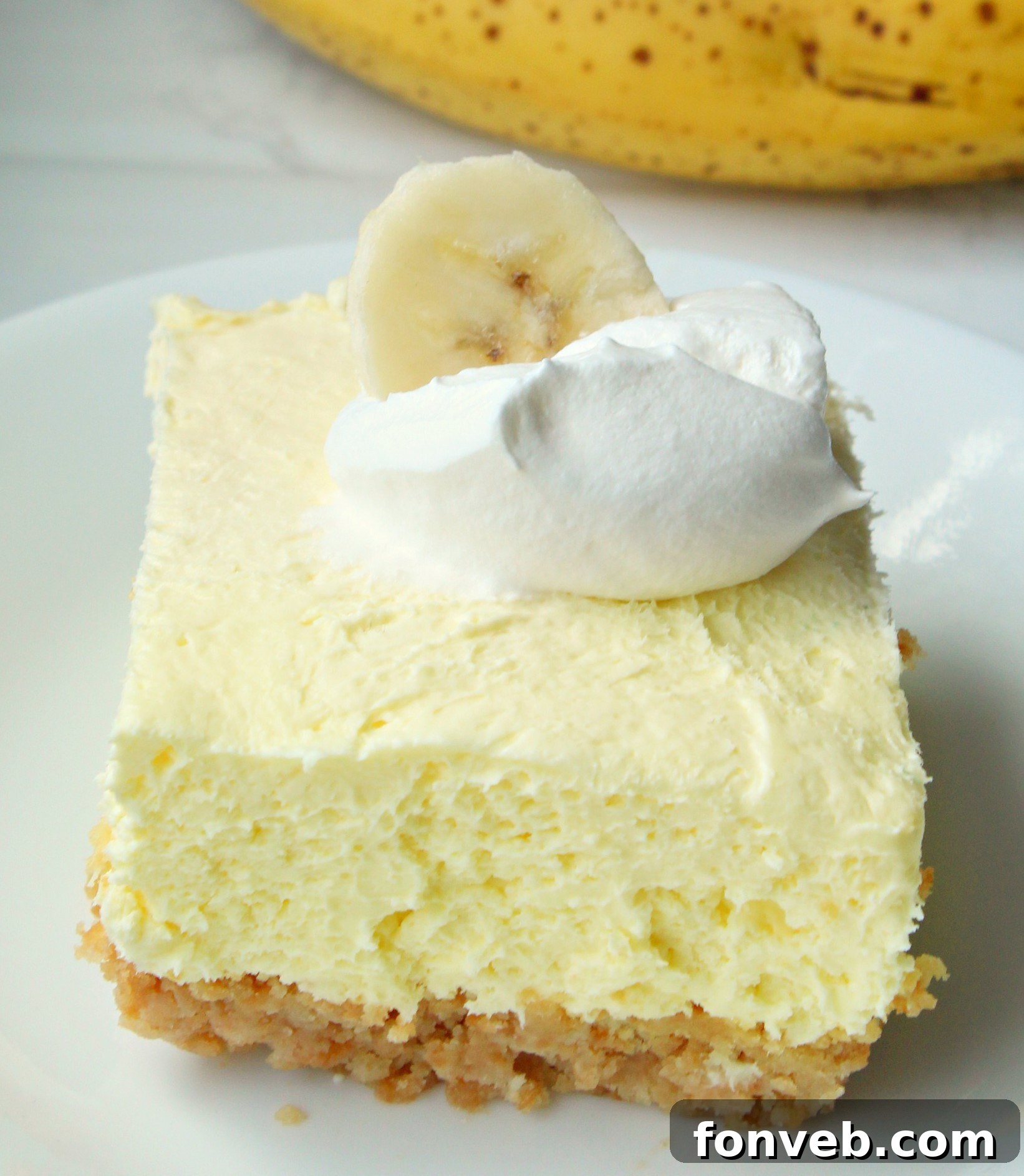 Close-up of a neatly sliced Banana Cream Cheesecake Bar showing distinct layers and a smooth finish.