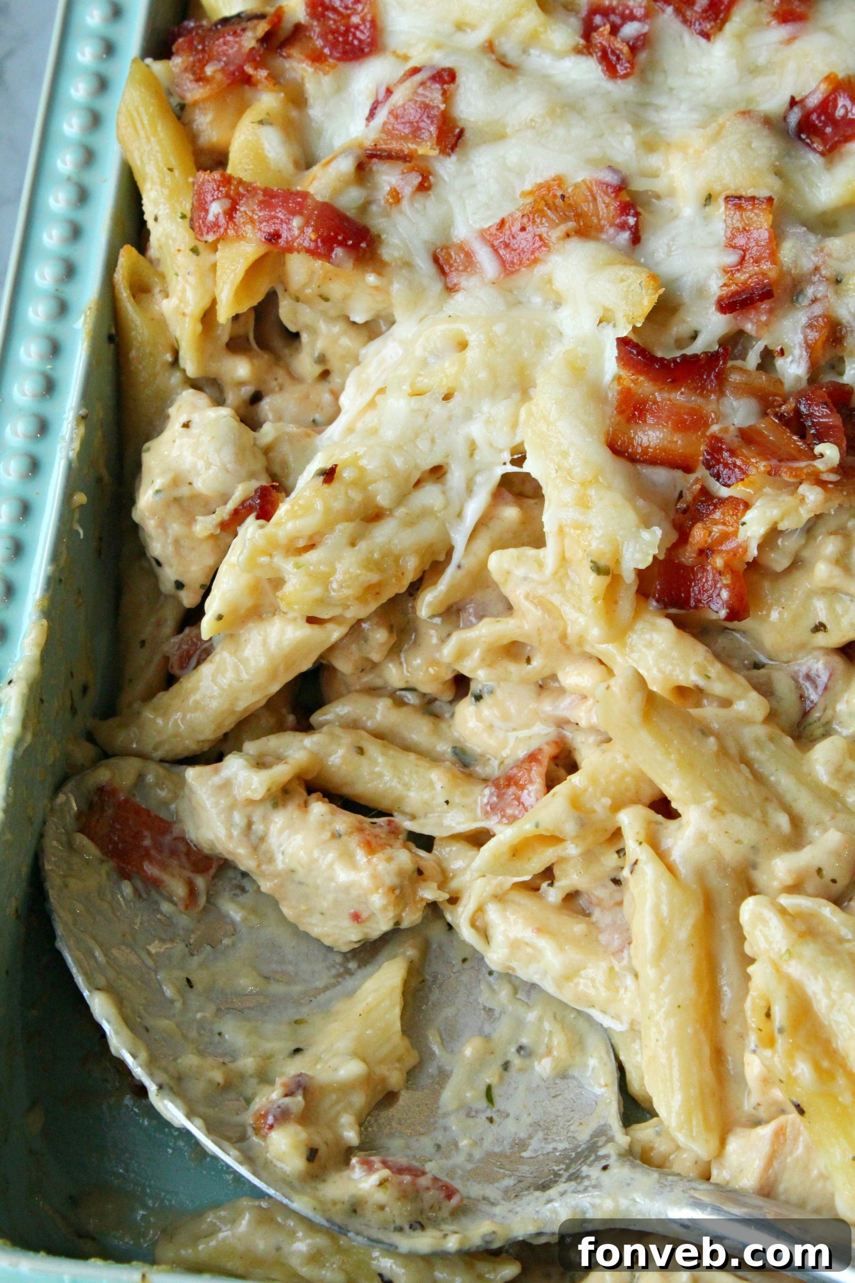Close-up of a bubbling, golden-brown Chicken Bacon Ranch Penne Pasta Bake fresh from the oven, showing melted cheese and visible chicken pieces.