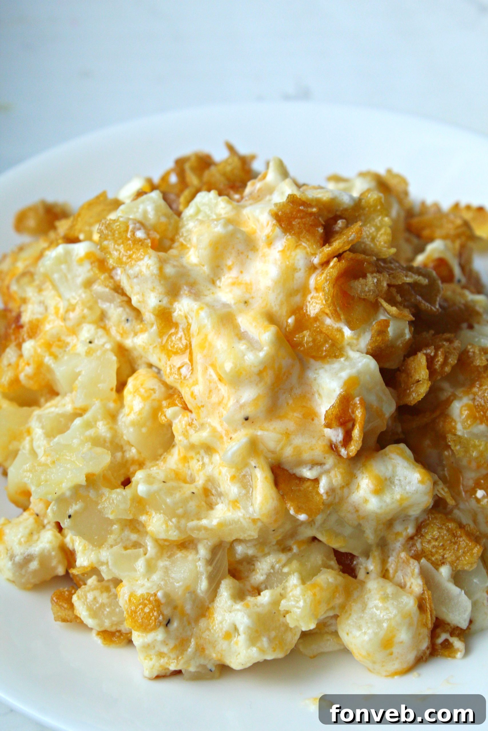 A serving of Funeral Potatoes on a white plate, garnished with fresh parsley