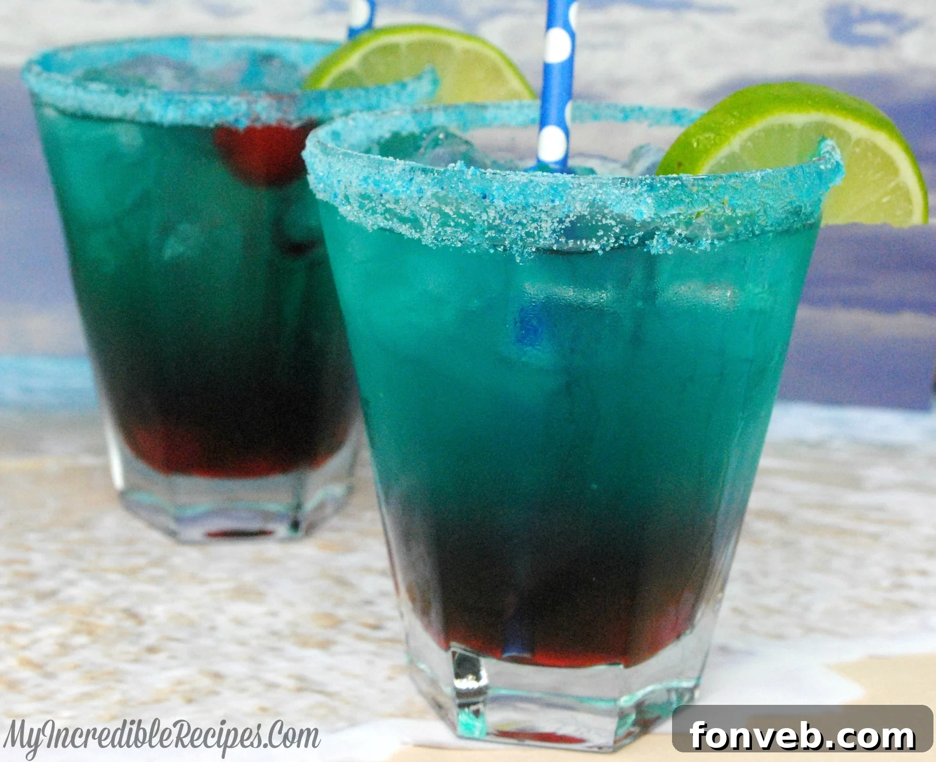 A vibrant Shark Bite cocktail with blue-green liquid and red grenadine streaks, garnished with a cherry.