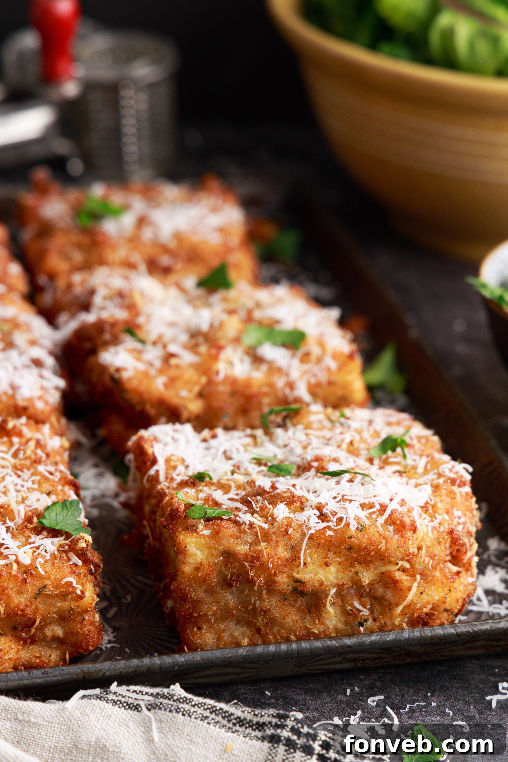 Golden Lasagna Crunch 2 Golden brown deep fried lasagna square on a white plate