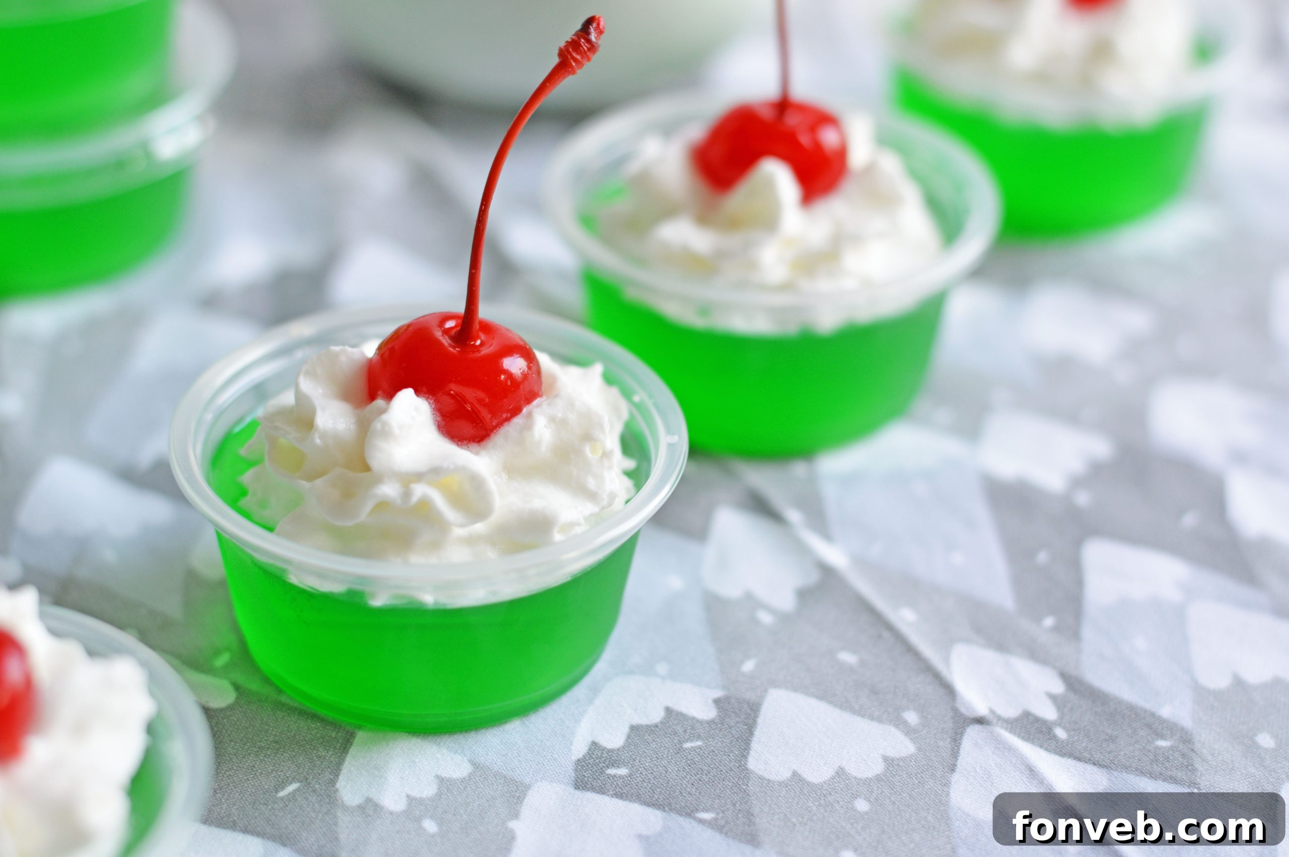 Close-up of Grinch Jello Shots with a blurry festive background