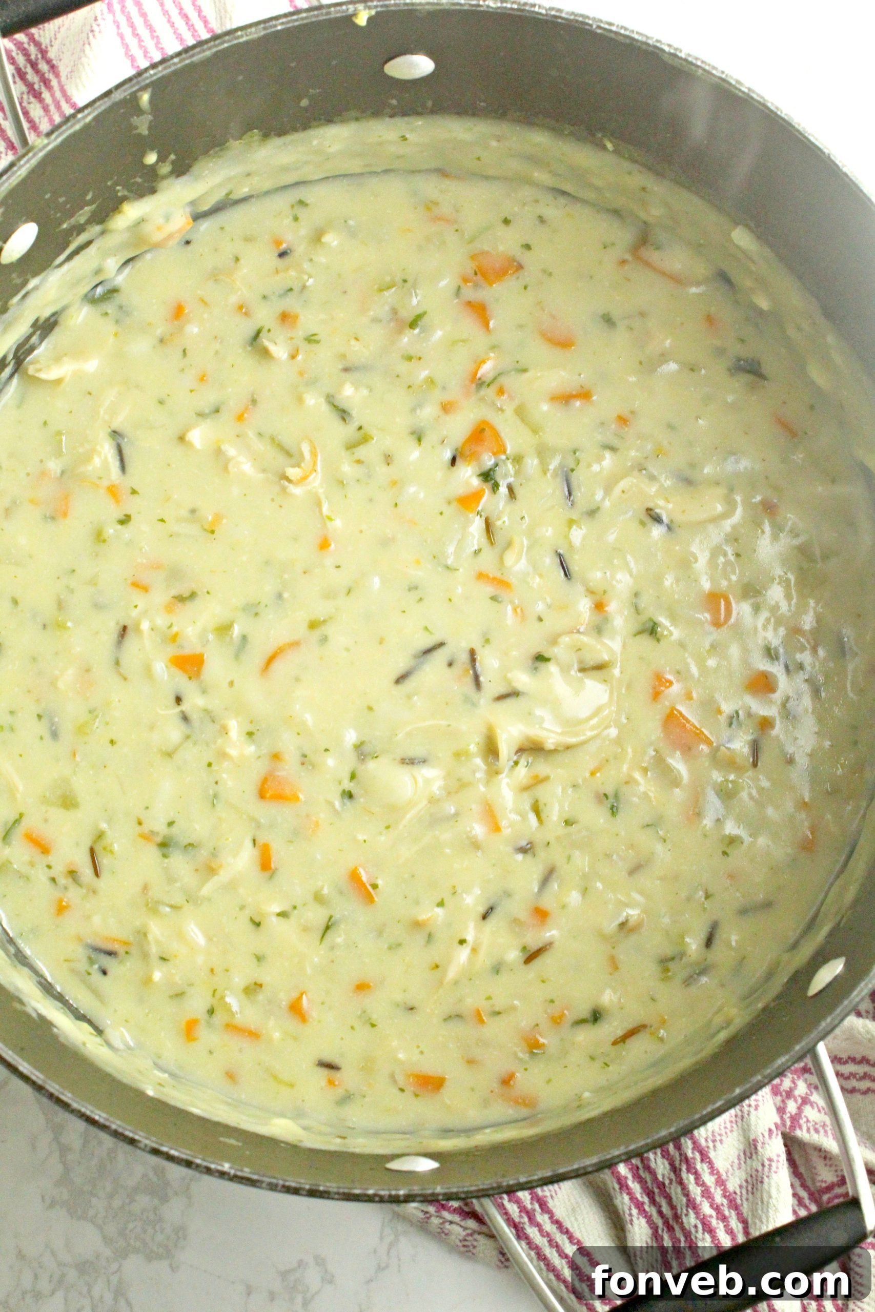 A large pot of chicken and wild rice soup simmering on the stovetop.