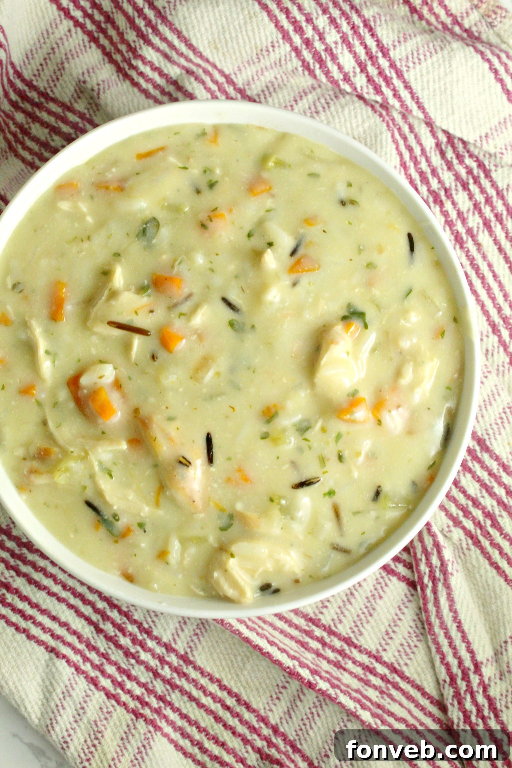 Various ingredients for chicken and wild rice soup laid out on a cutting board.