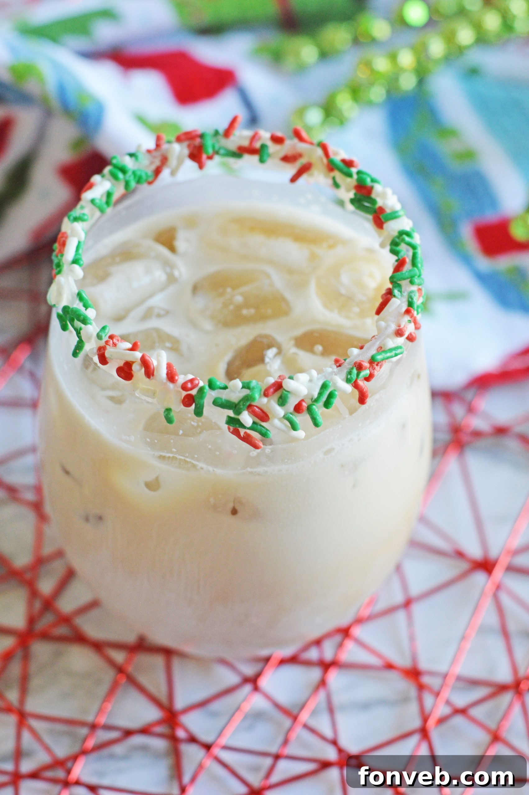 Christmas Cookie Cocktail being poured into a sprinkle-rimmed glass.