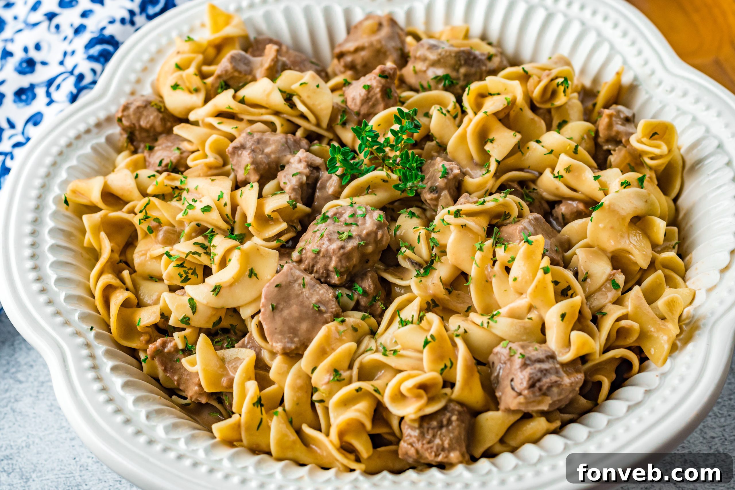 Fresh parsley being sprinkled over a bowl of Crock Pot Beef and Noodles