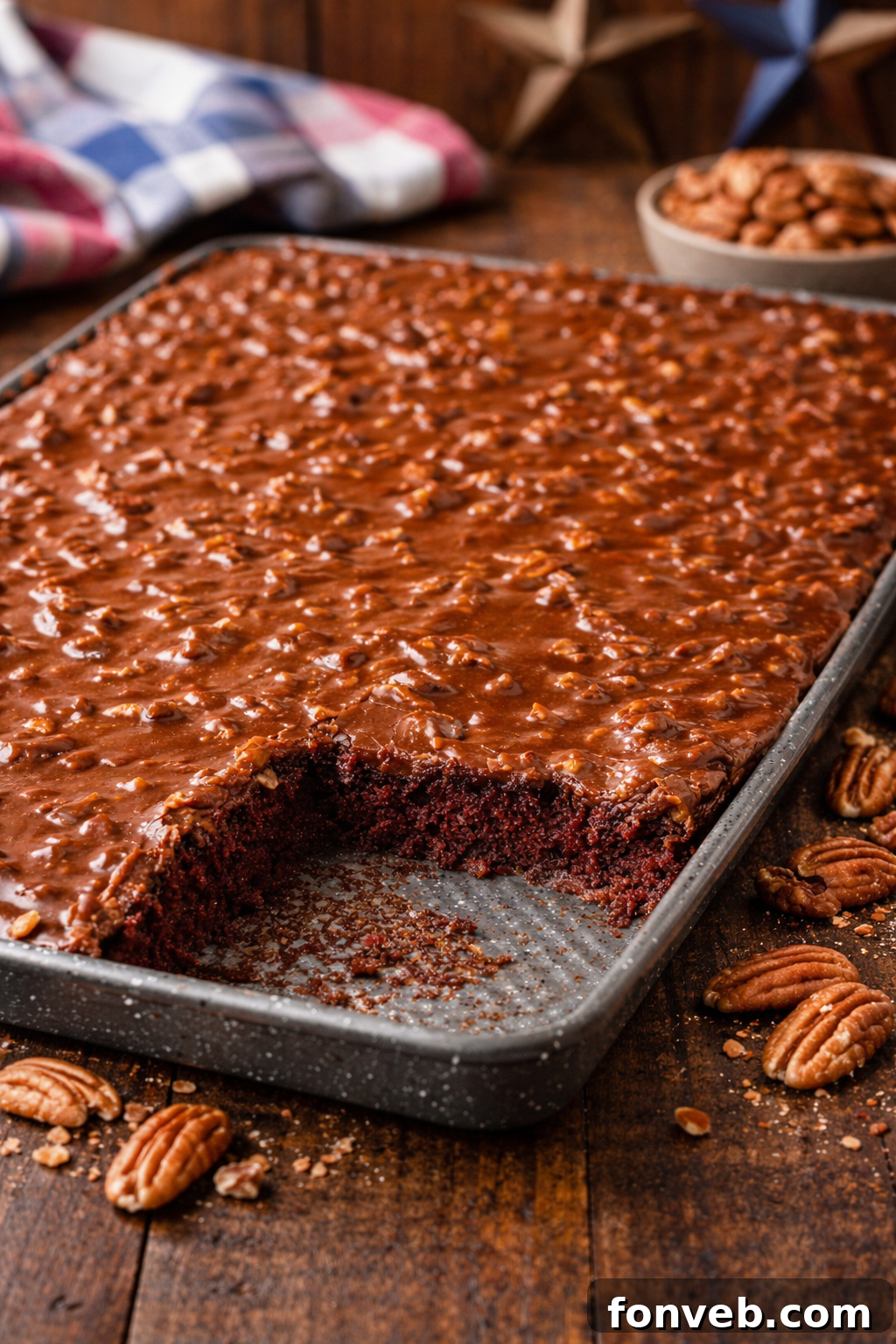 Texas Sheet Cake on a dark wood table in a baking sheet with a slice missing 