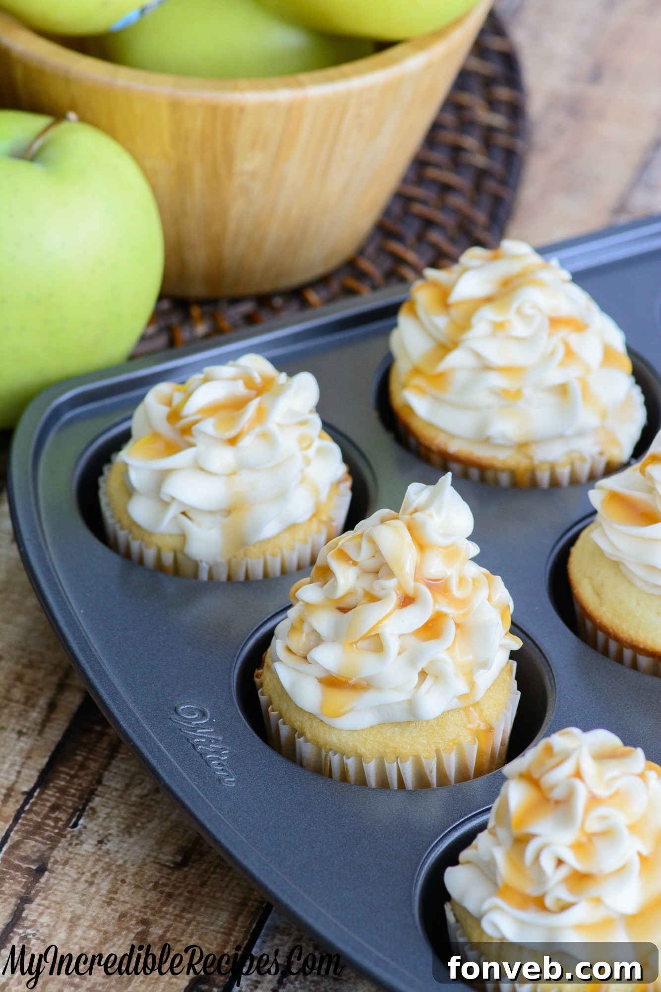 A batch of freshly baked caramel apple cupcakes, some frosted and some ready for decoration.