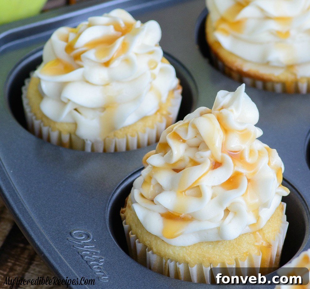 Several caramel apple cupcakes arranged on a rustic wooden board, ready to be enjoyed.