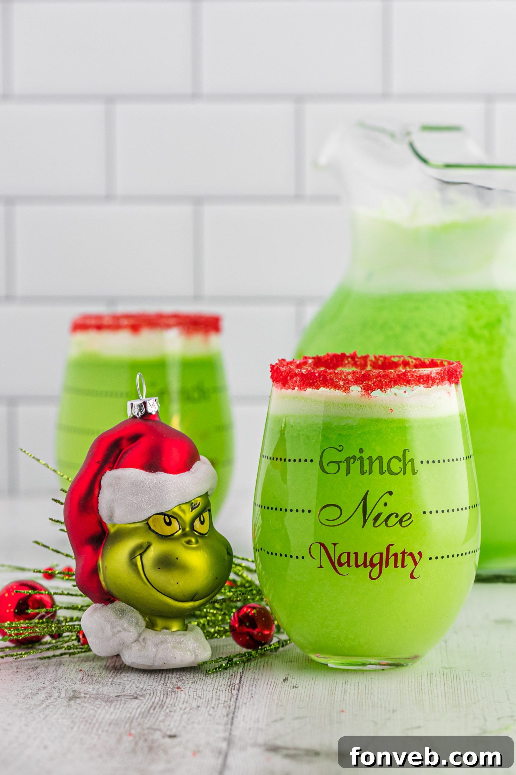 Vibrant green Grinch Punch in a festive glass with a red sugar rim, ready for a Christmas party.