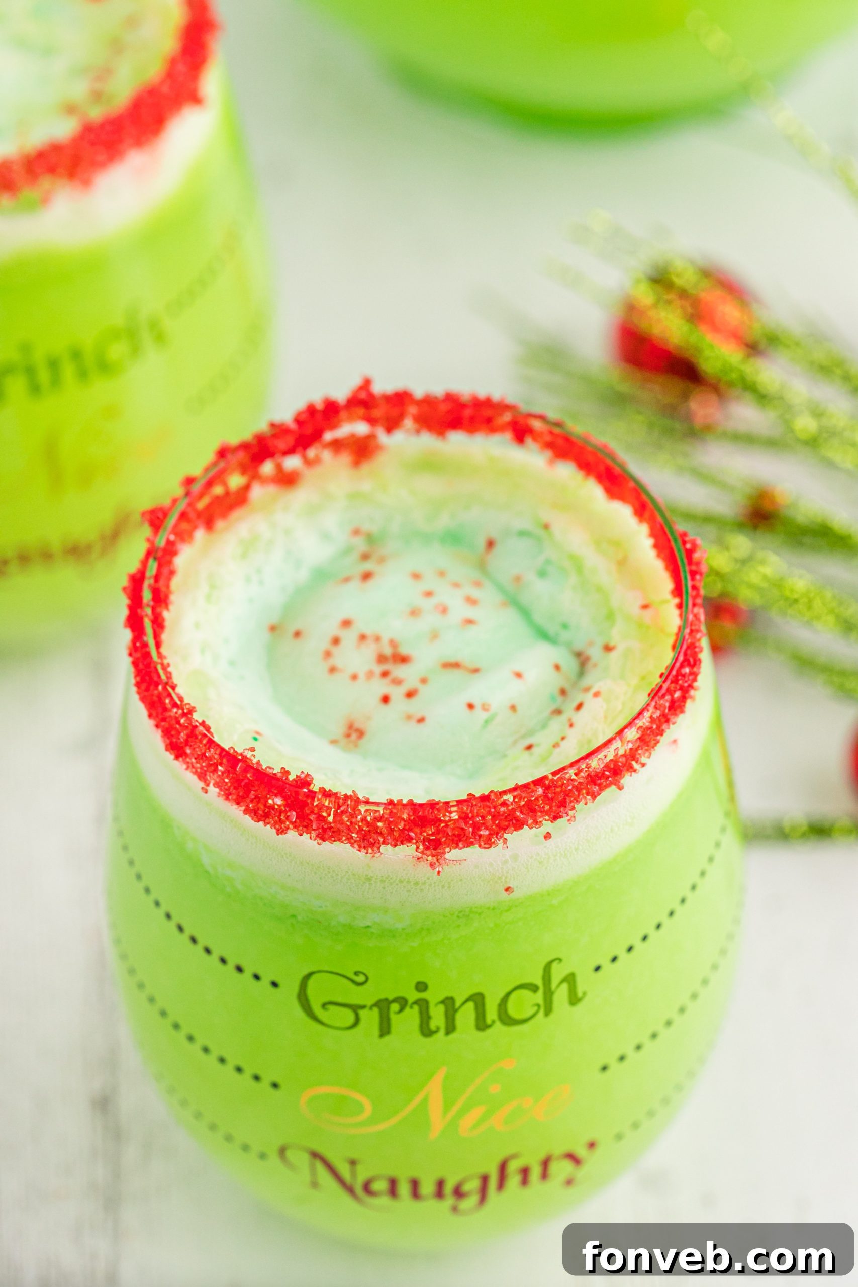 Close-up of a glass of Grinch Punch with a festive red sugar rim, sparkling and ready to serve.