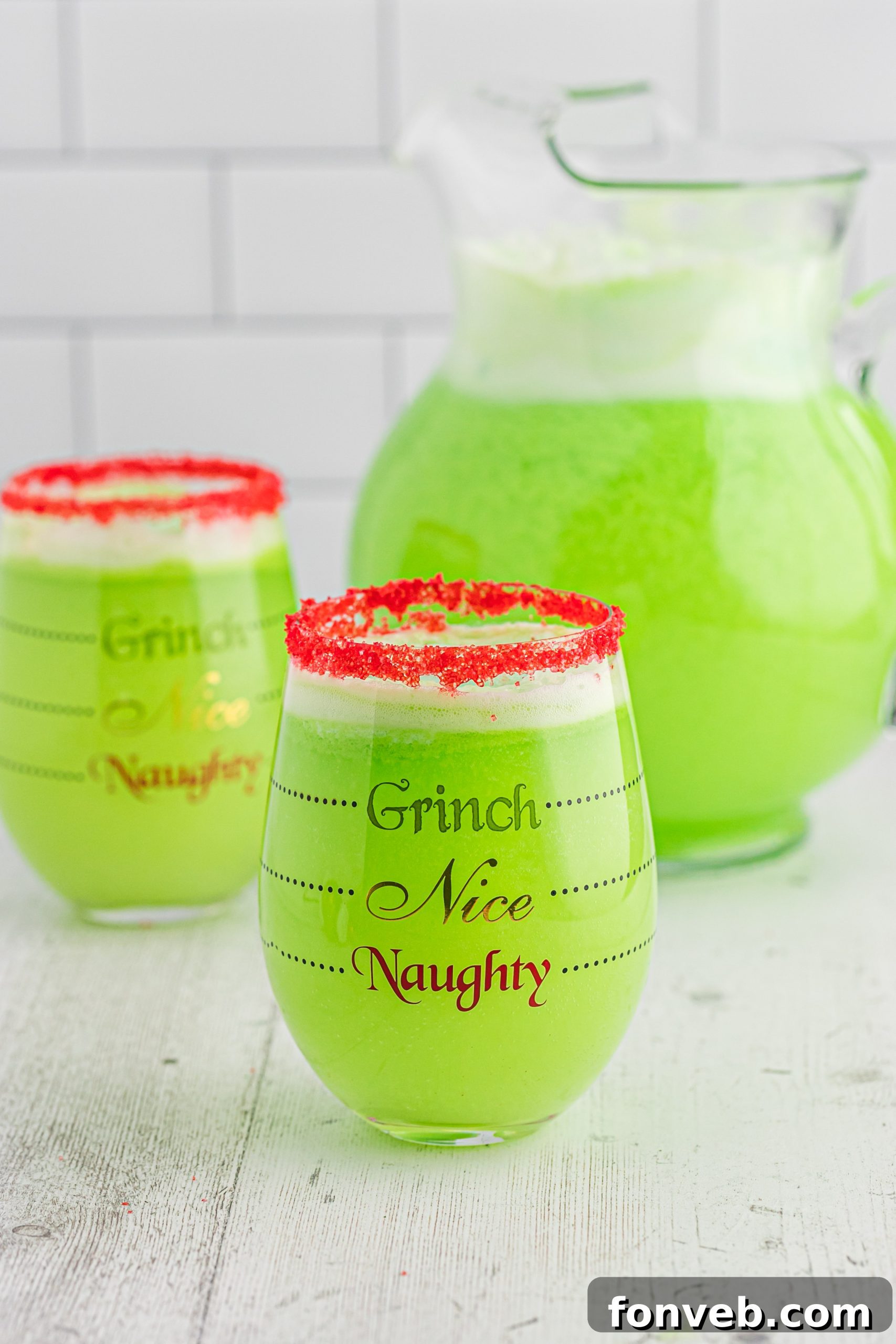 A festive holiday table setting with a pitcher of Grinch Punch, garnished with lime slices.