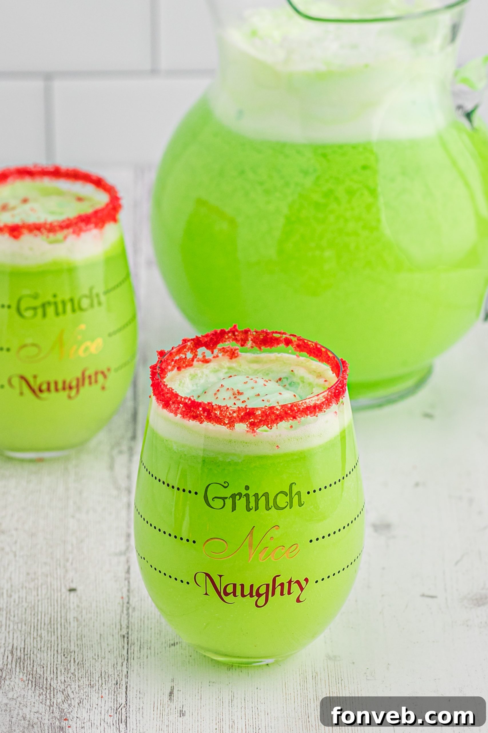 Glasses of Grinch Punch lined up, each with a red sugar rim, ready to be enjoyed.