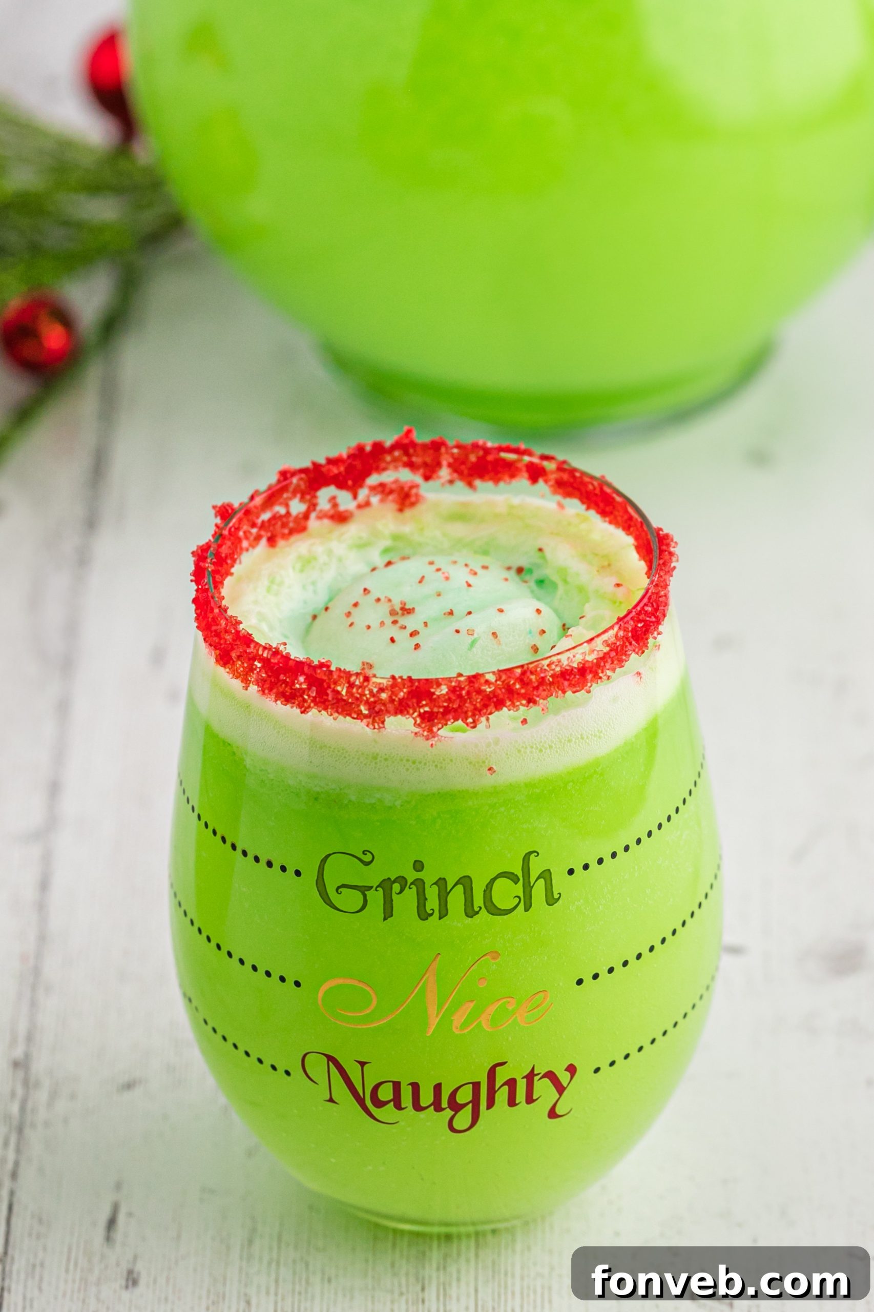 Grinch-themed glasses filled with green punch and garnished with candy, sitting on a festive table.
