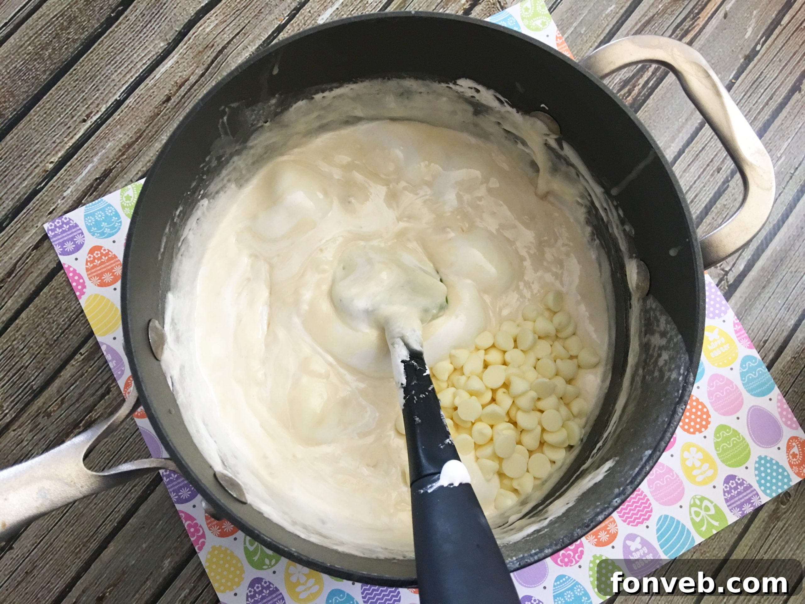 Two hands gently holding a slice of rainbow-layered Unicorn Fudge, highlighting its soft texture and distinct color separation, against a blurred background.