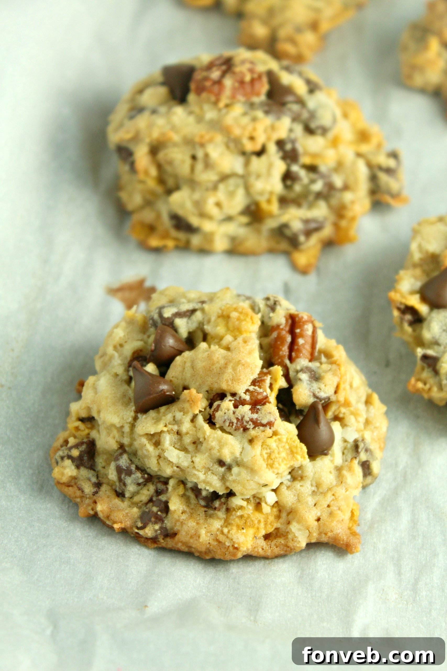 A plate of freshly baked Cowboy Cookies, with one broken in half to show the soft, chewy interior with melted chocolate.