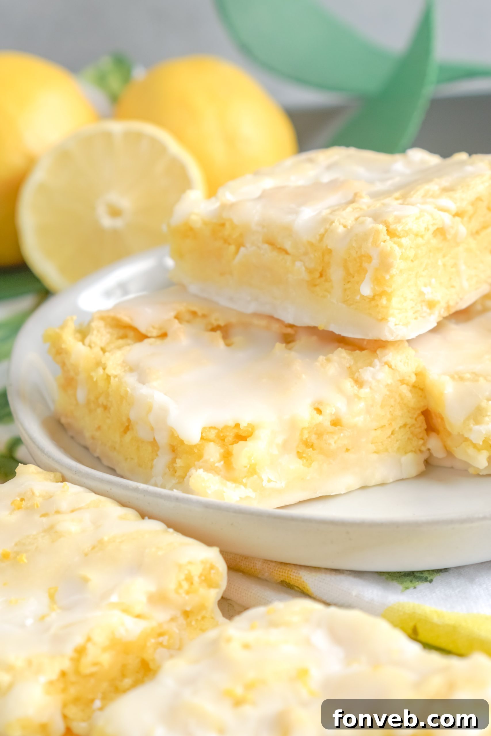 A collection of freshly baked lemon brownies with a glistening lemon glaze, arranged beautifully on a rustic wooden surface.
