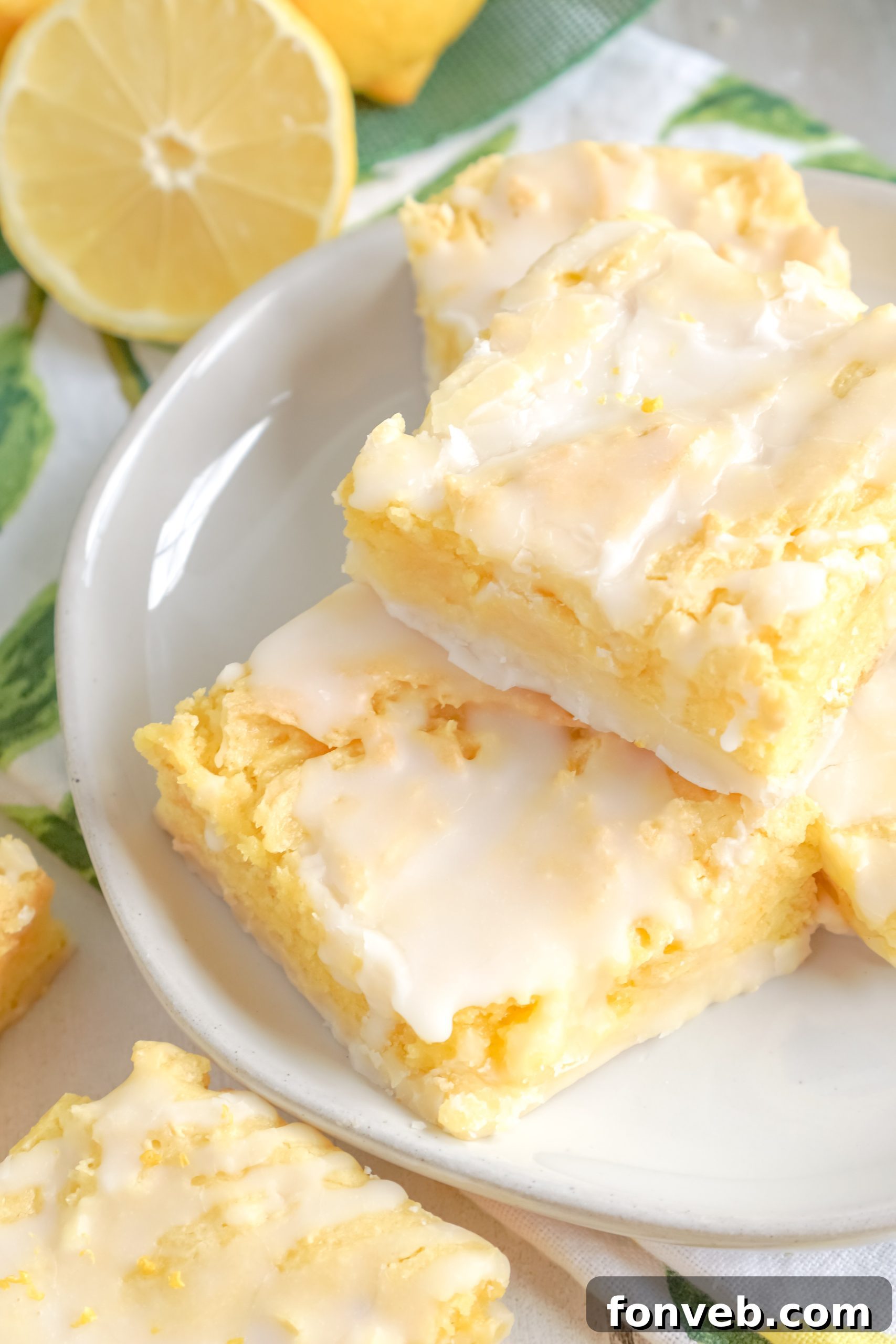 A single piece of lemon brownie, freshly cut and drizzled with bright yellow glaze, served on a white background.