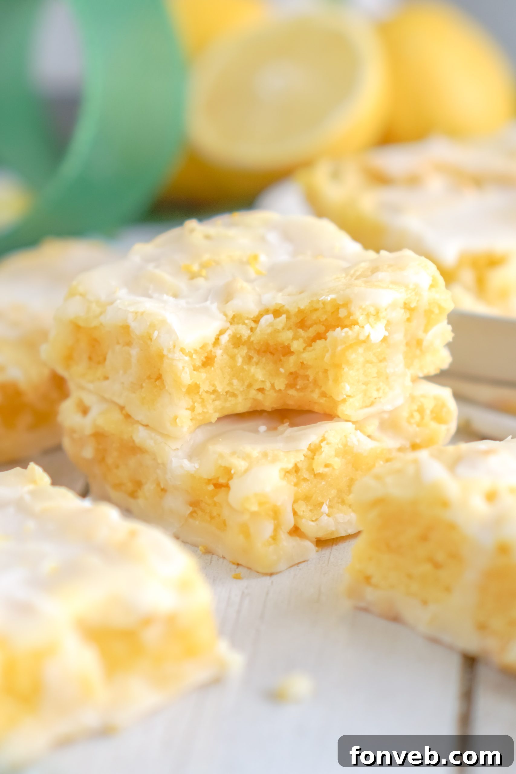 Eight perfectly square lemon brownies, coated with a sweet glaze, arranged on a white serving platter.