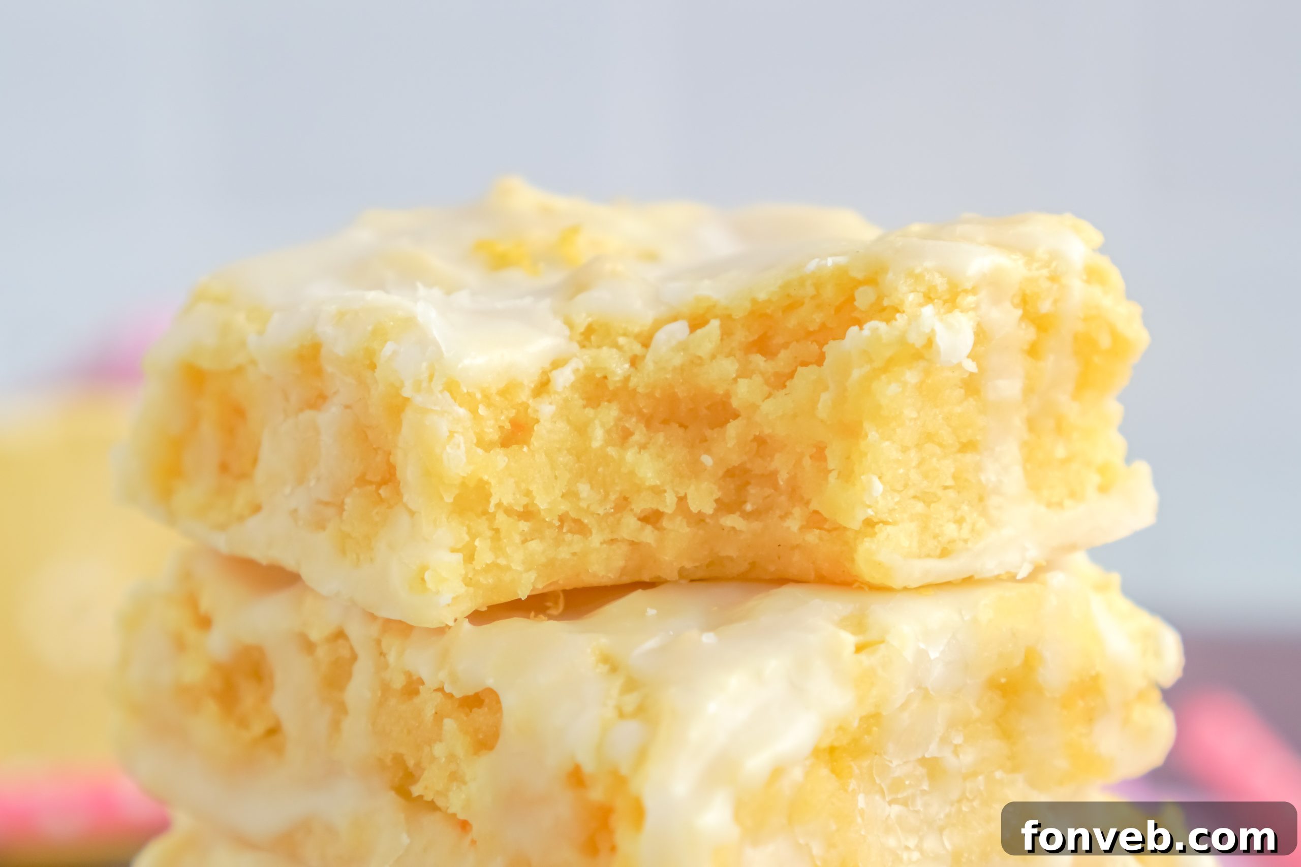 A cutting board with a large slab of lemon brownies, a knife poised to cut, revealing the moist interior.