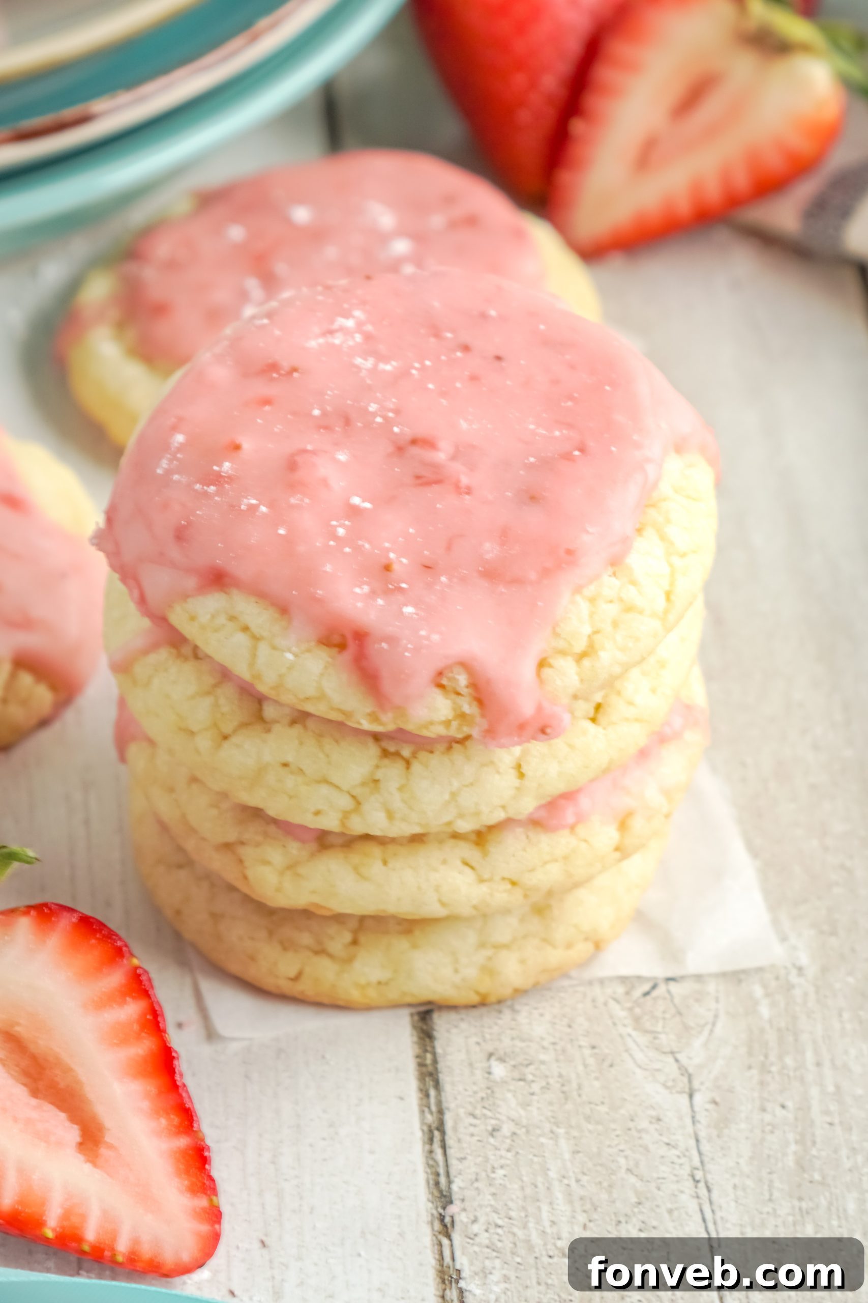 A delicious sugar cookie half-dipped in strawberry glaze, showing the consistency and sheen of the glaze.