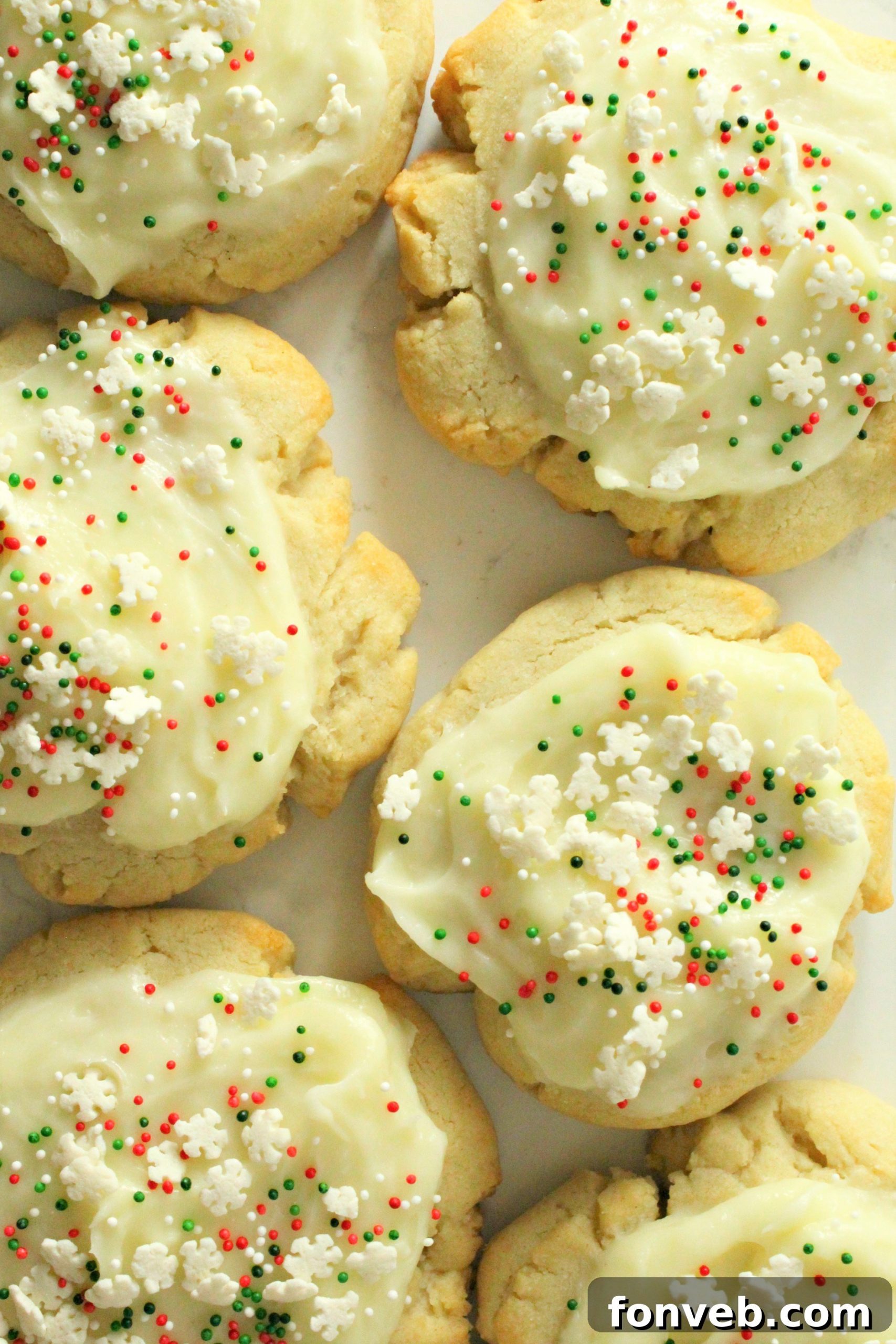 Freshly baked Swig Sugar Cookies with light pink buttercream frosting and festive sprinkles, arranged on a baking sheet.